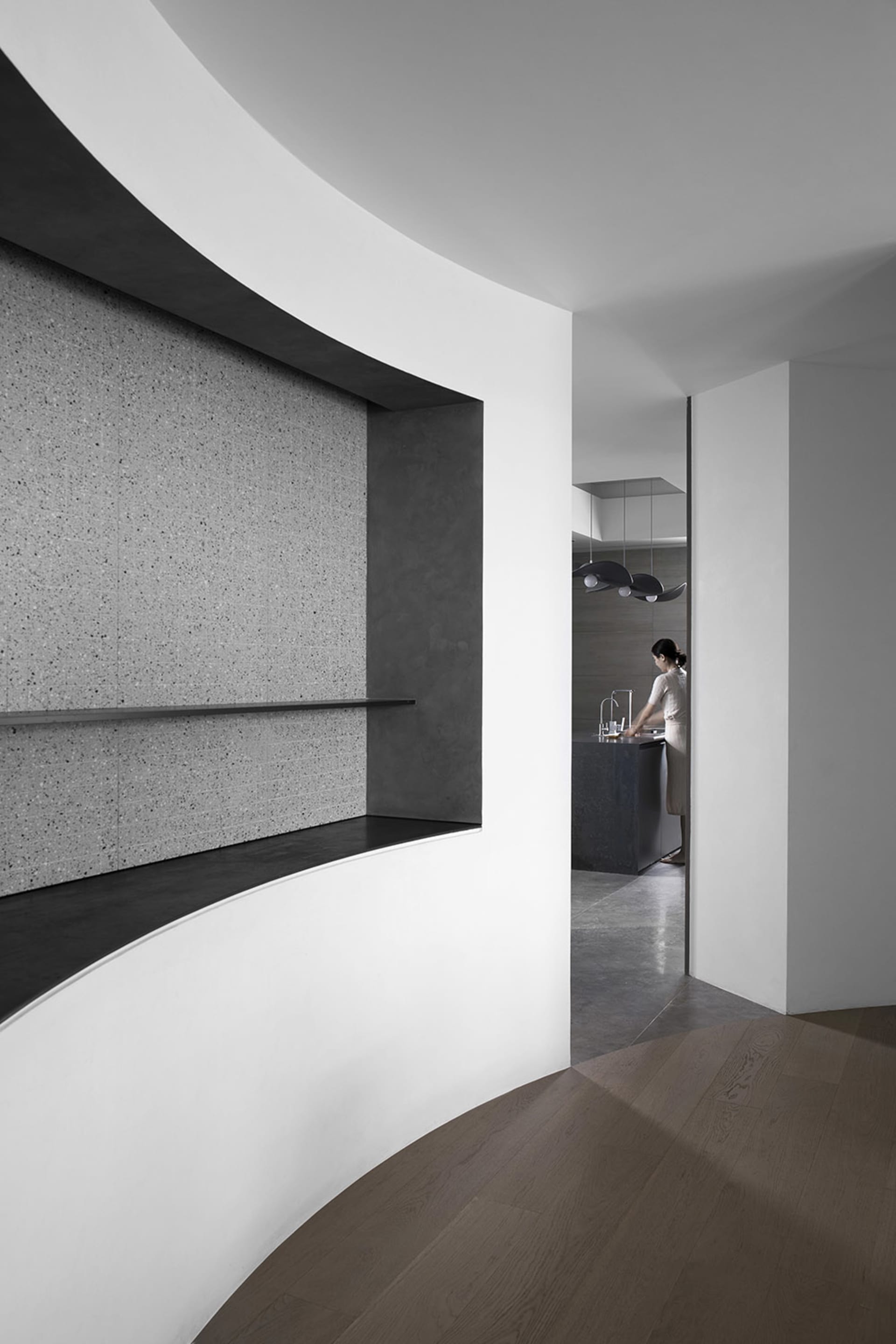 Modern minimalist kitchen with concrete walls, wooden flooring, and metallic accents