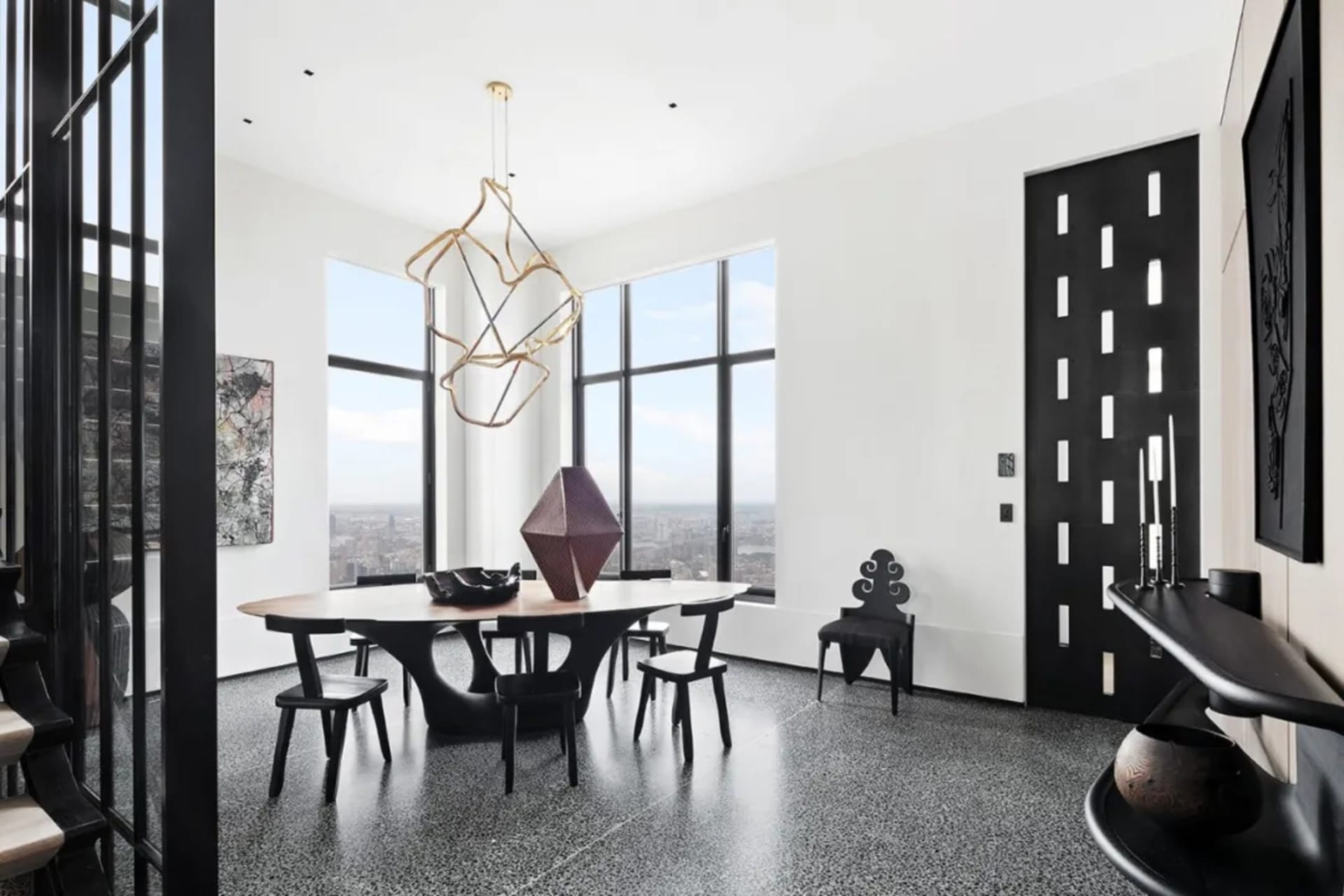 Modern dining room with a metal table and chairs, featuring large windows and a unique pendant light.