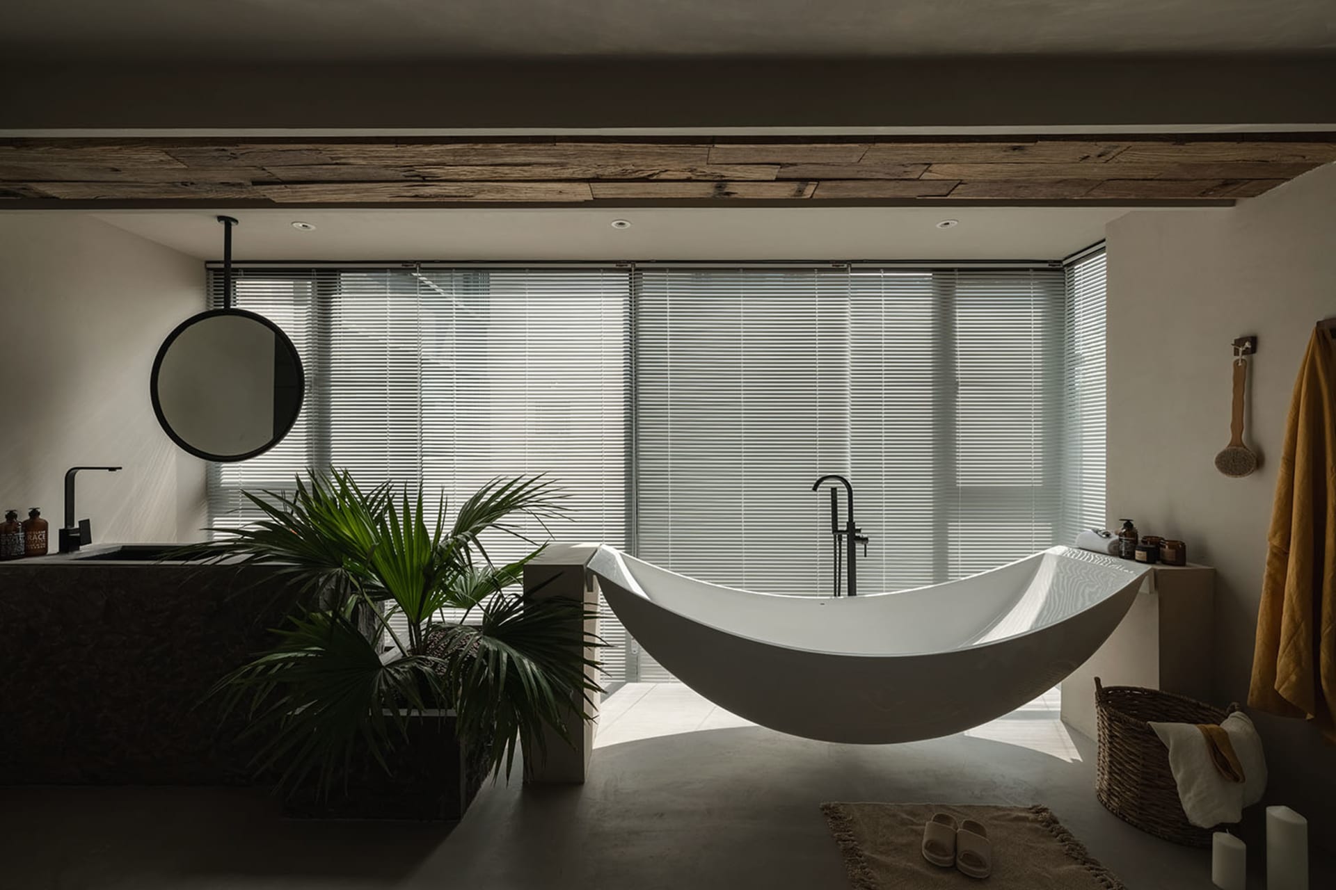 Modern minimalist bathroom with a white concrete bathtub, large windows, and a plant.