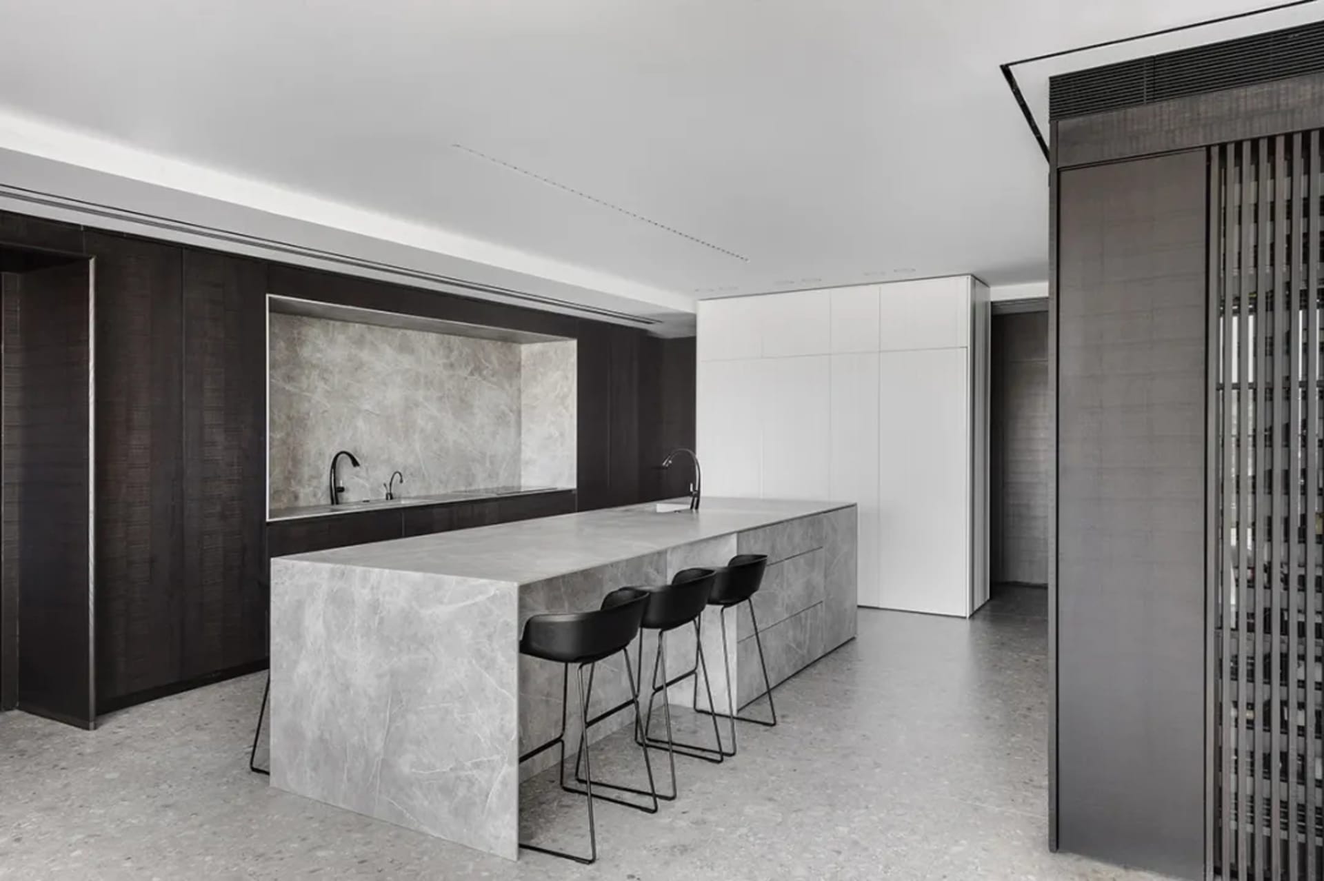 A modern kitchen with a marble island and concrete flooring.