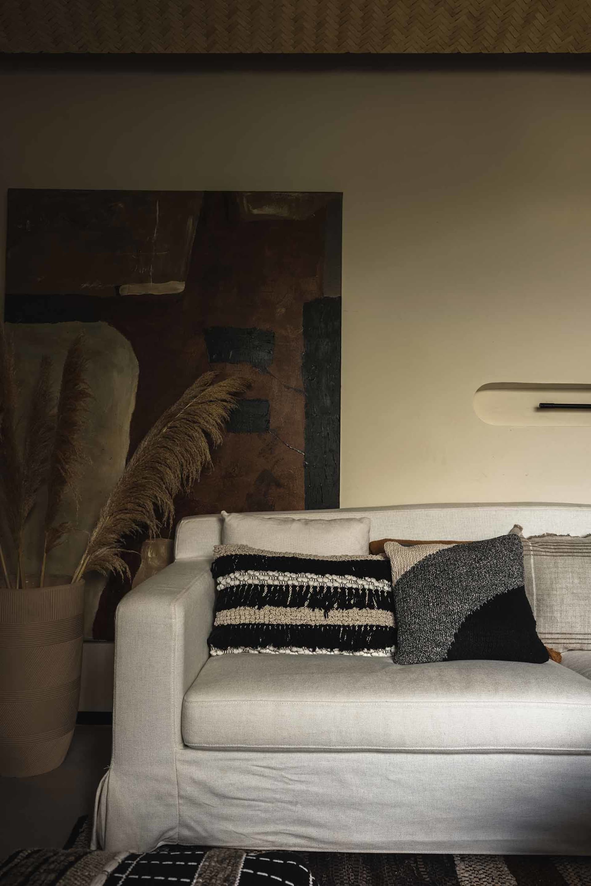 Modern living room featuring contemporary furniture, cushions, and an abstract painting.