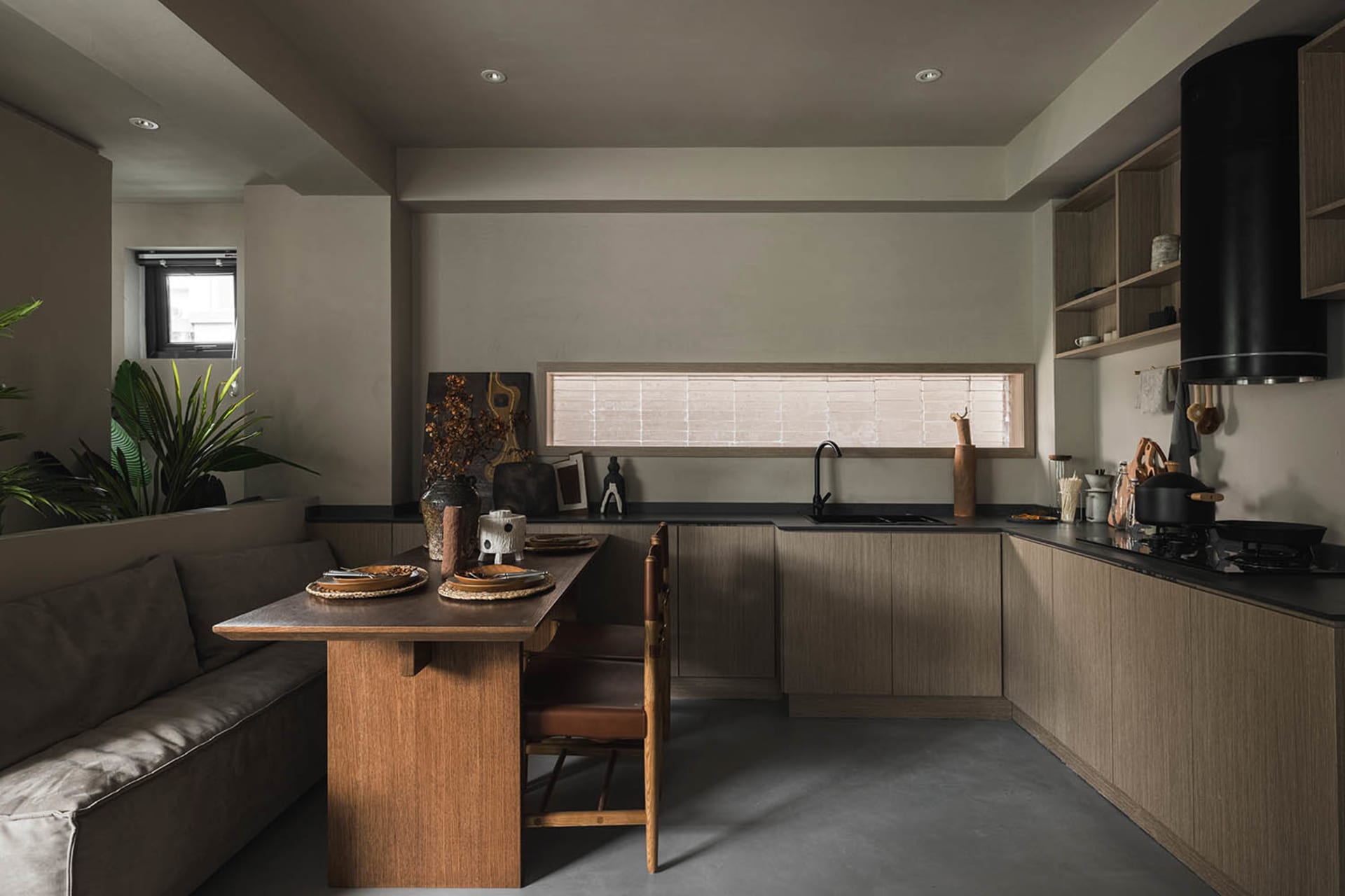 A modern minimalist kitchen with dark wood cabinetry and a long table.