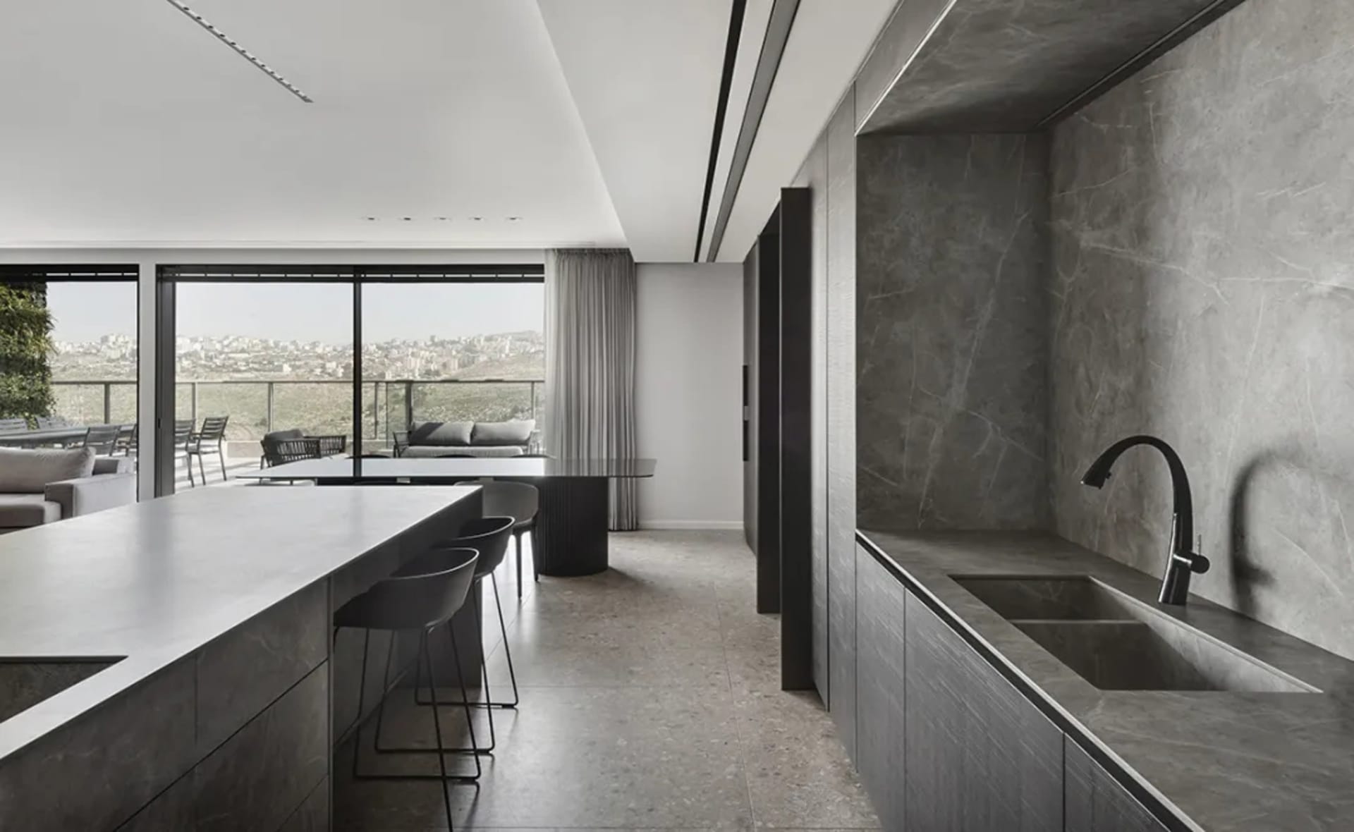 A modern residential kitchen with a marble island and concrete flooring.