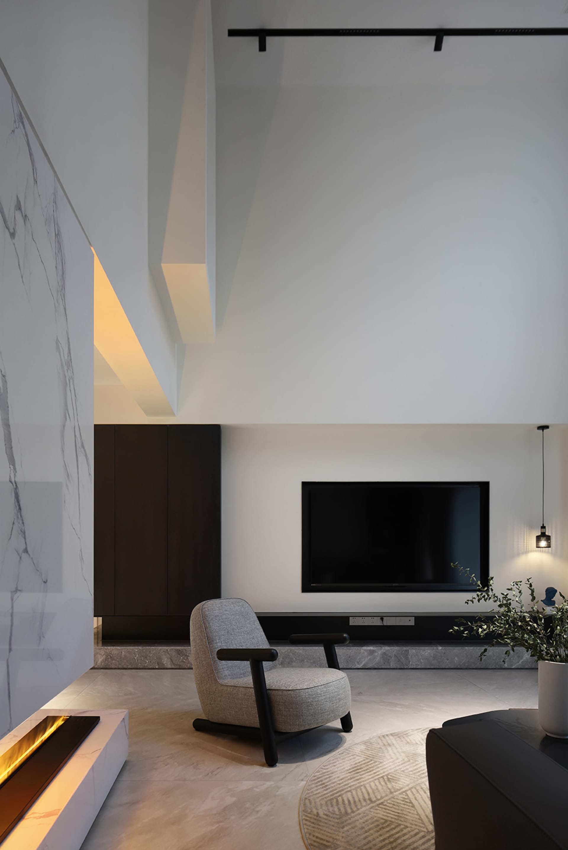 A modern living room featuring a concrete floor, minimalist design, and a single armchair in front of a television.
