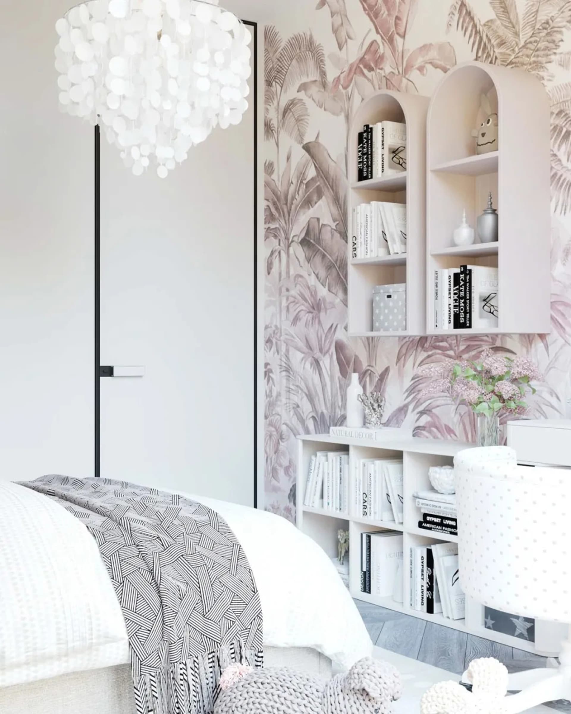 Modern bathroom with floral wallpaper, bookshelves, and a chandelier.