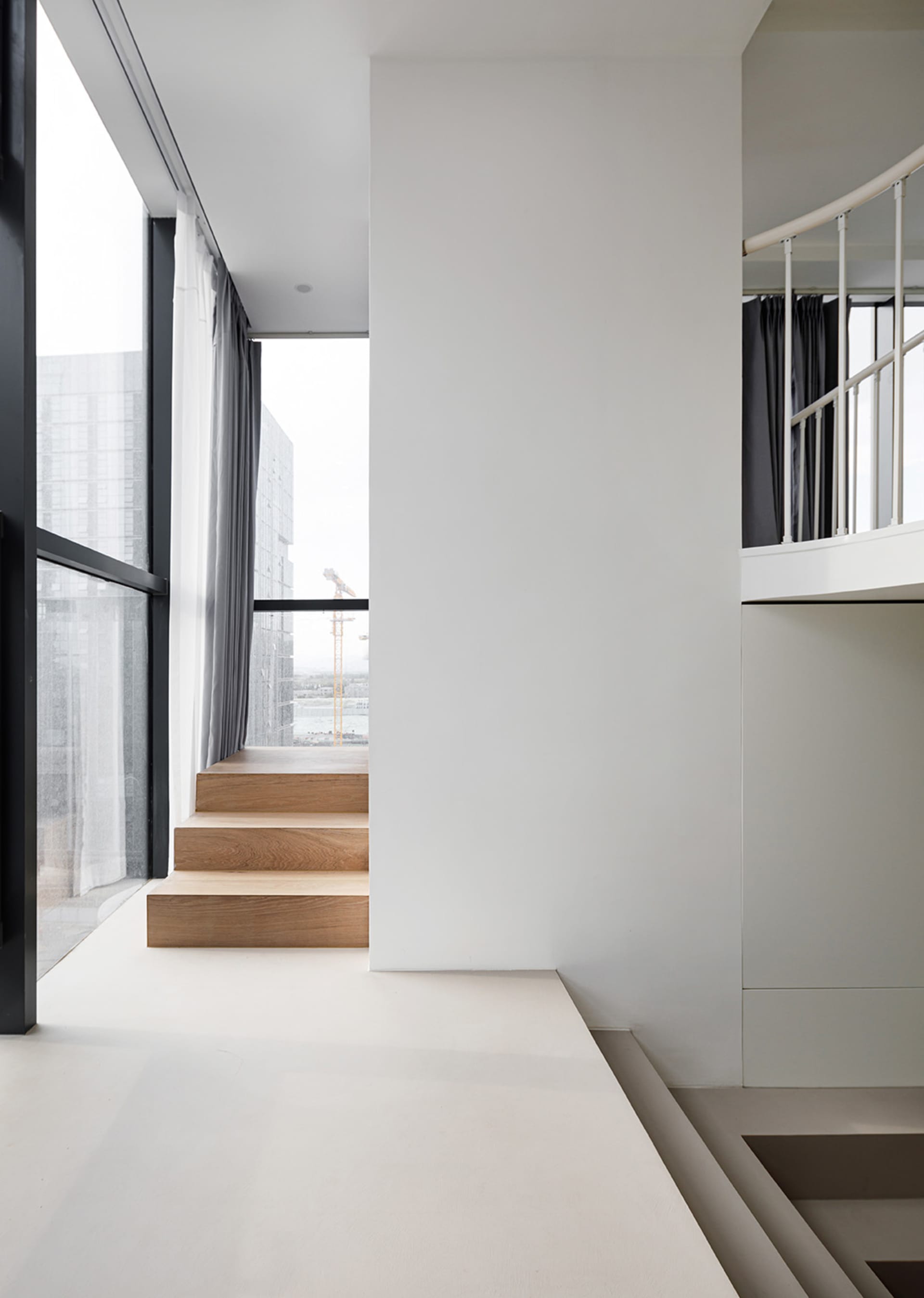 A modern interior space featuring a wooden staircase with large windows.