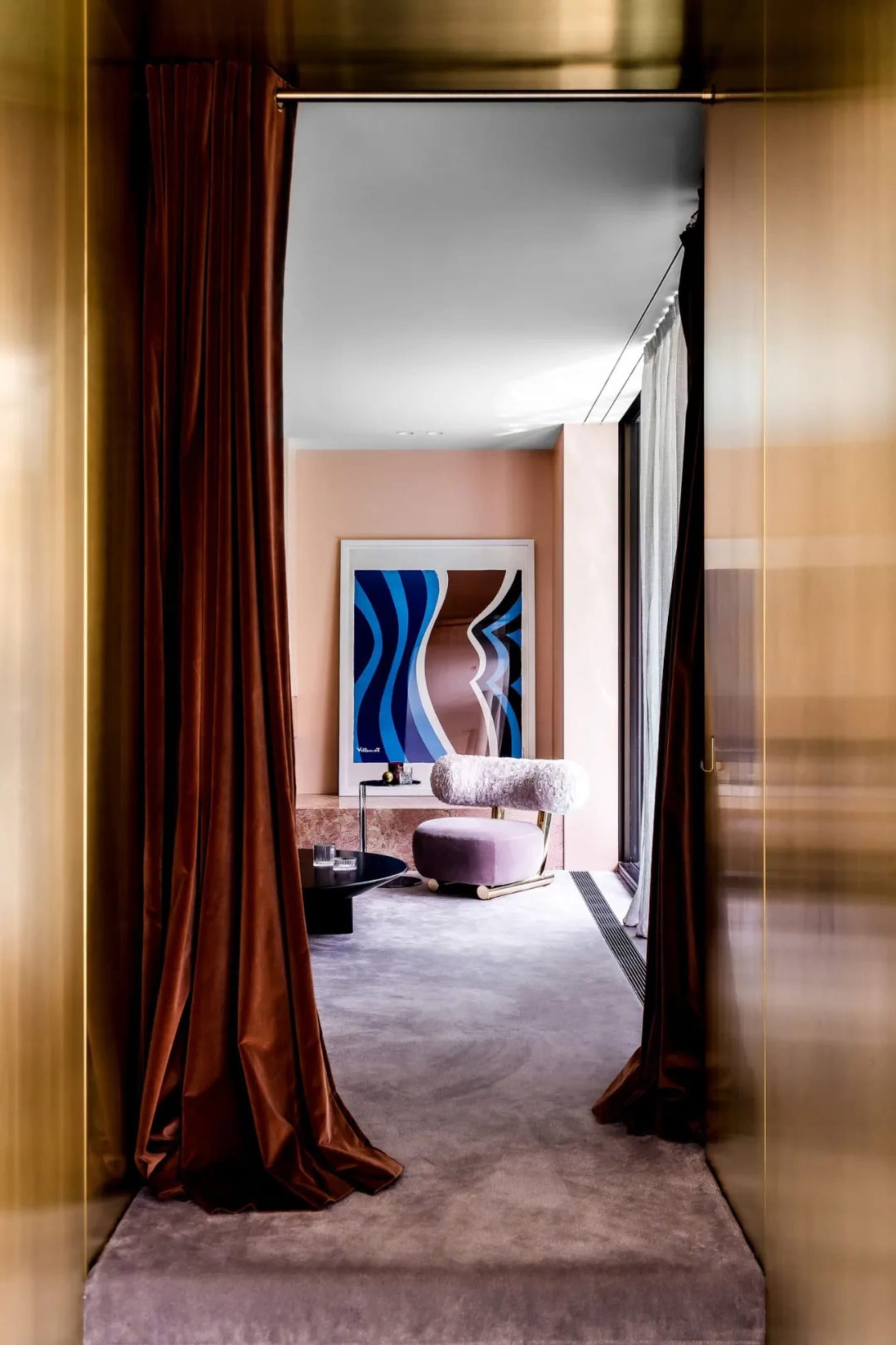 Modern interior space with velvet curtains, marble flooring, and contemporary artwork.