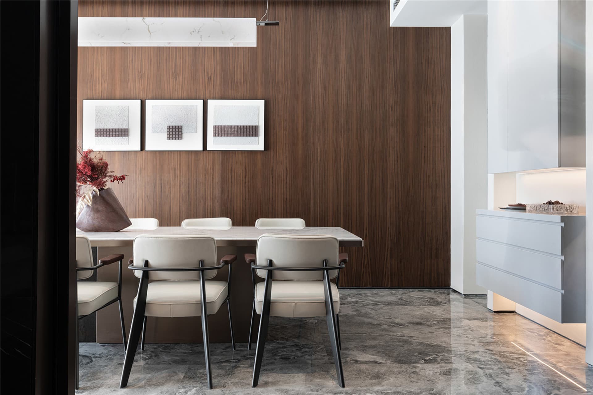 Modern dining room featuring a sleek marble table and chairs, with a wooden accent wall and white accents.
