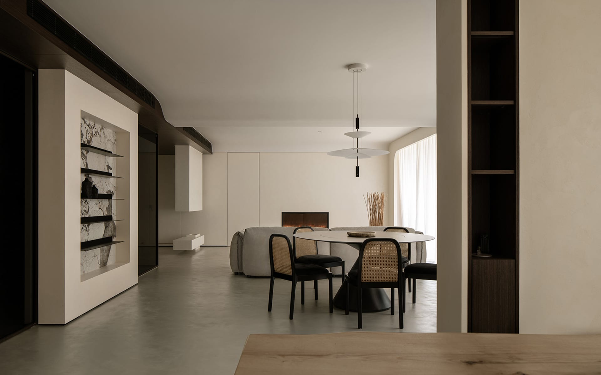 A minimalist living and dining room with neutral-toned materials and a sleek, modern design.