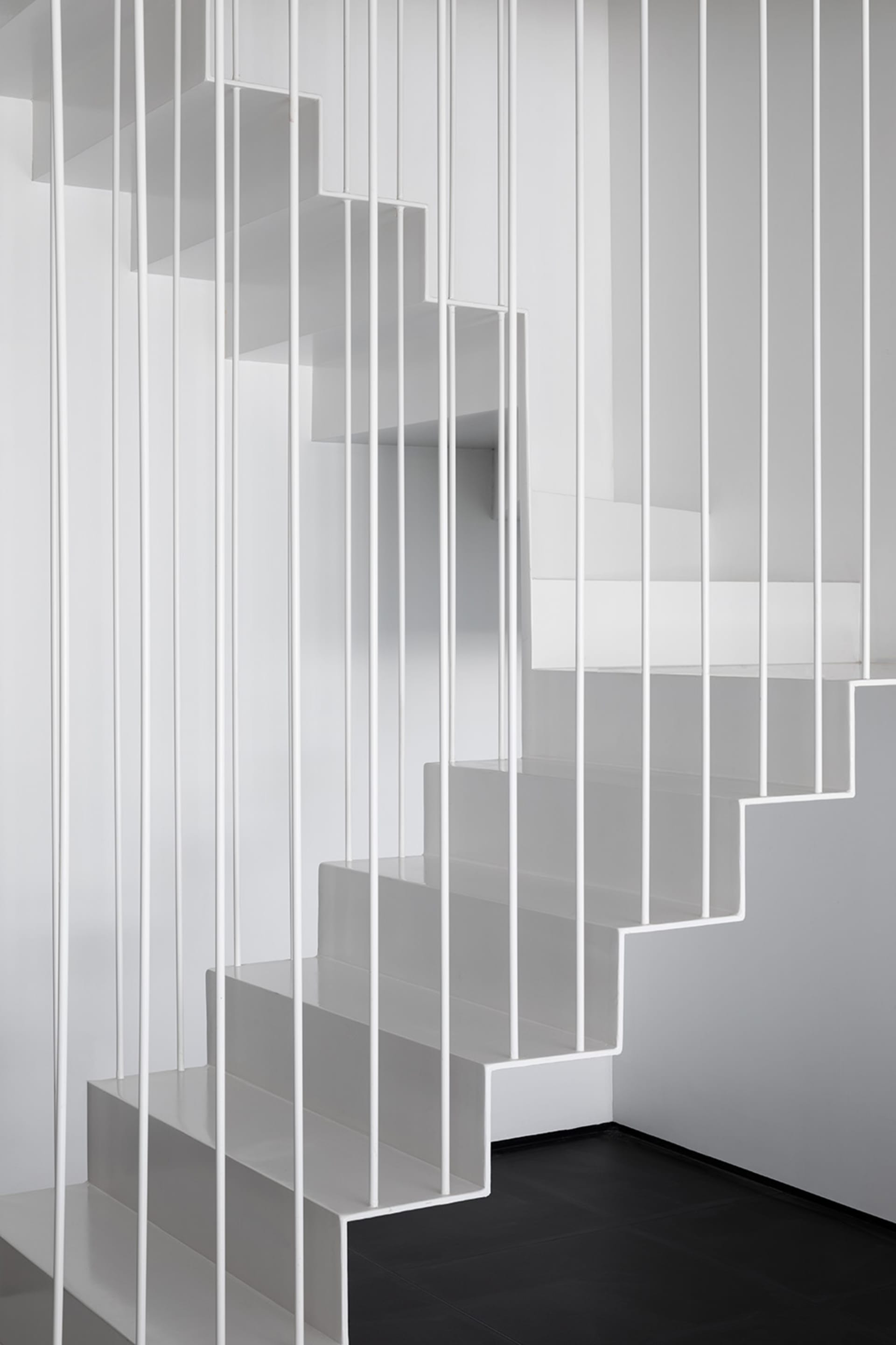 Modern, minimalist staircase with white metal railings and steps, viewed from above.