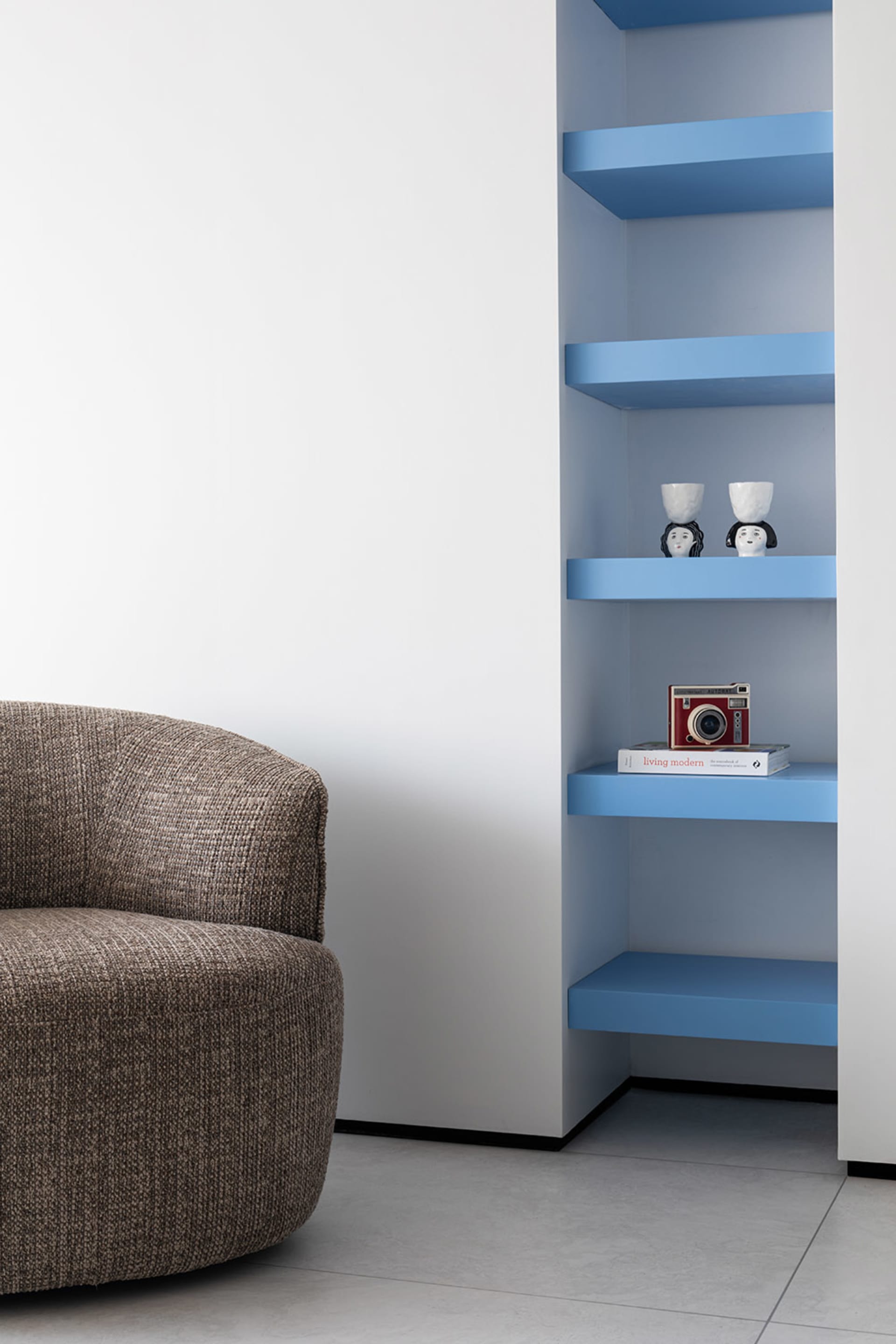 A modern living room featuring blue floating shelves with various decorative items including a red camera and two ceramic fig