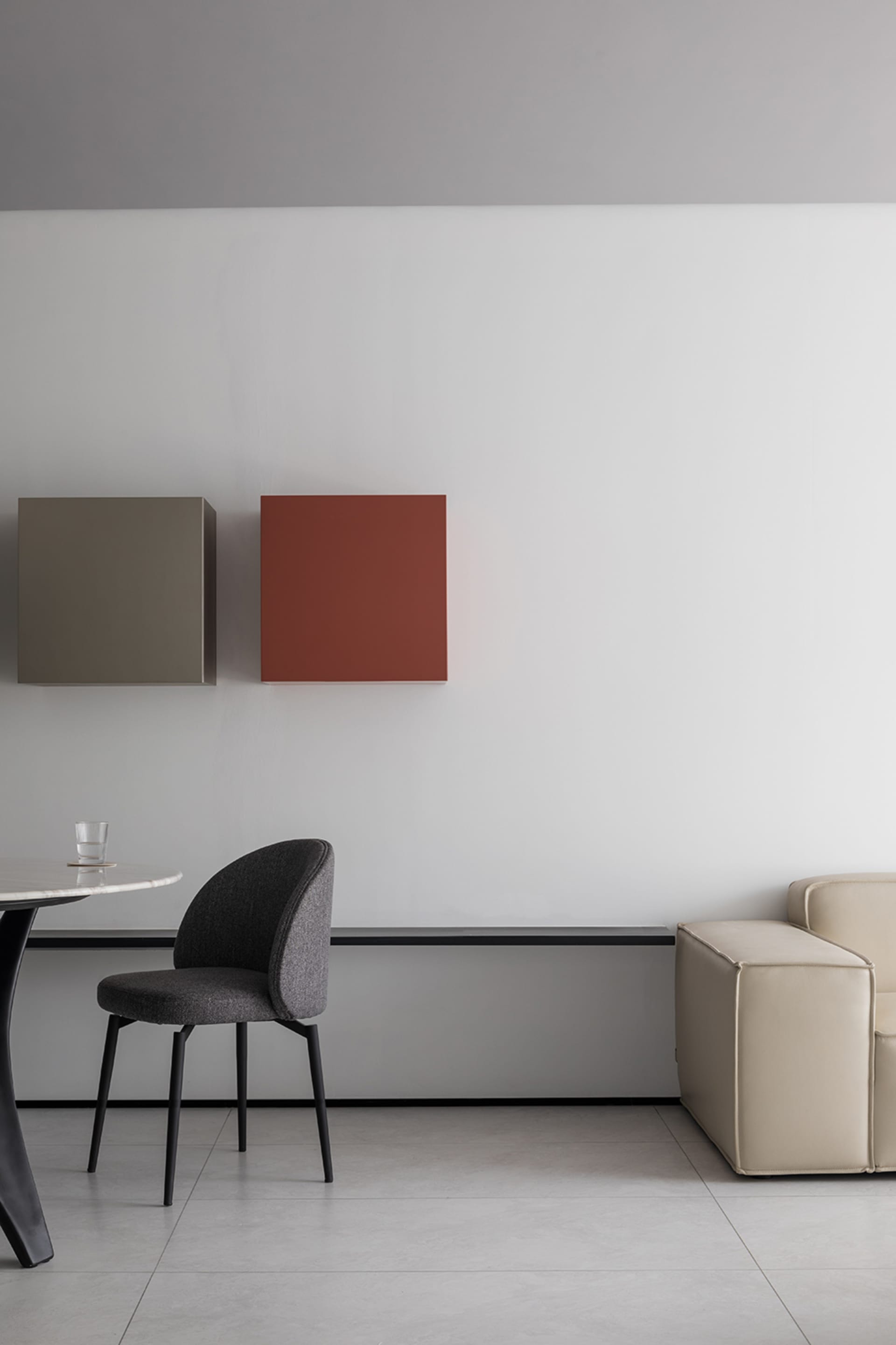 Modern minimalist living room with a beige sofa, a black dining chair, and geometric wall art.