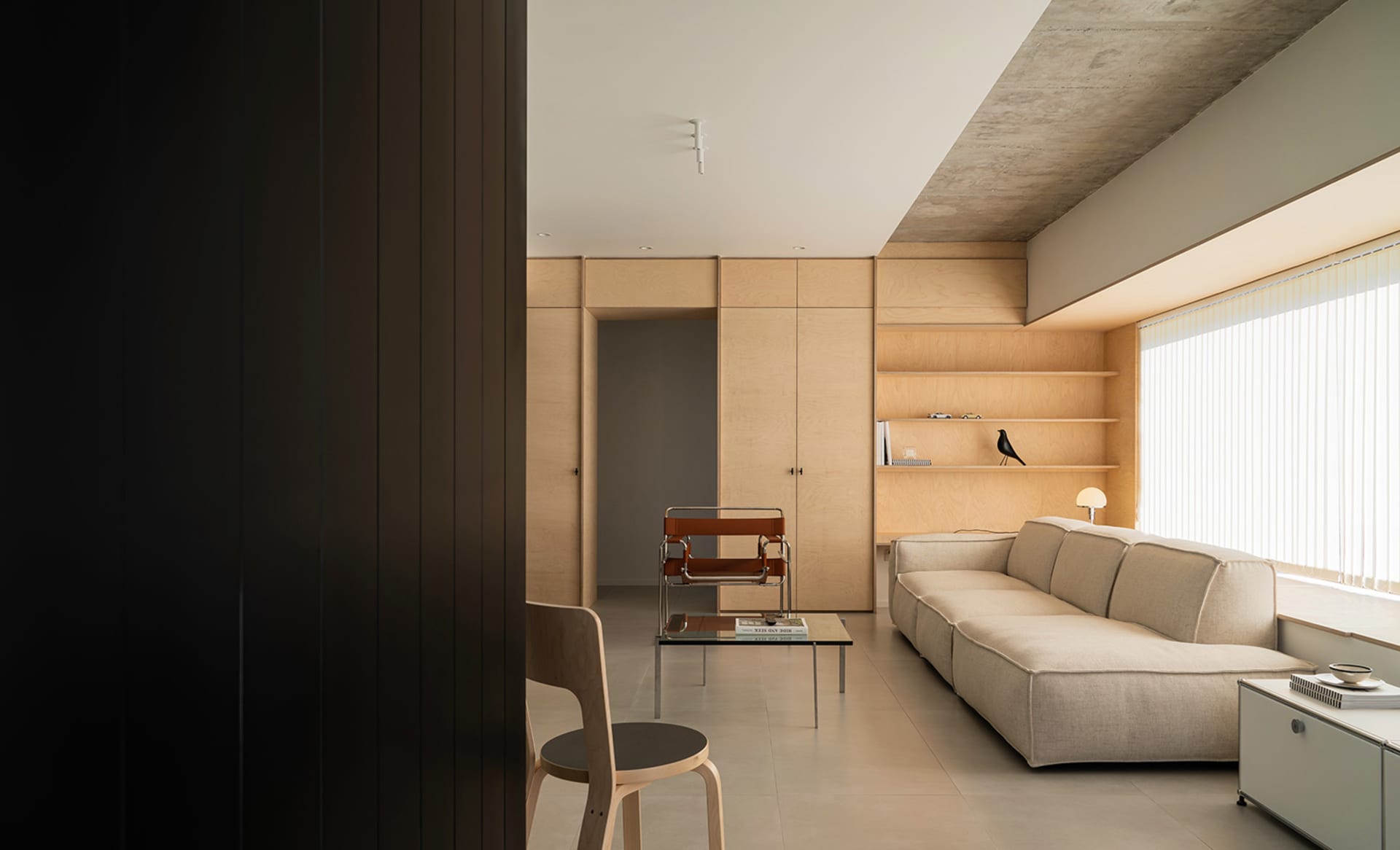 A modern minimalist living room with wooden furniture and shelves.