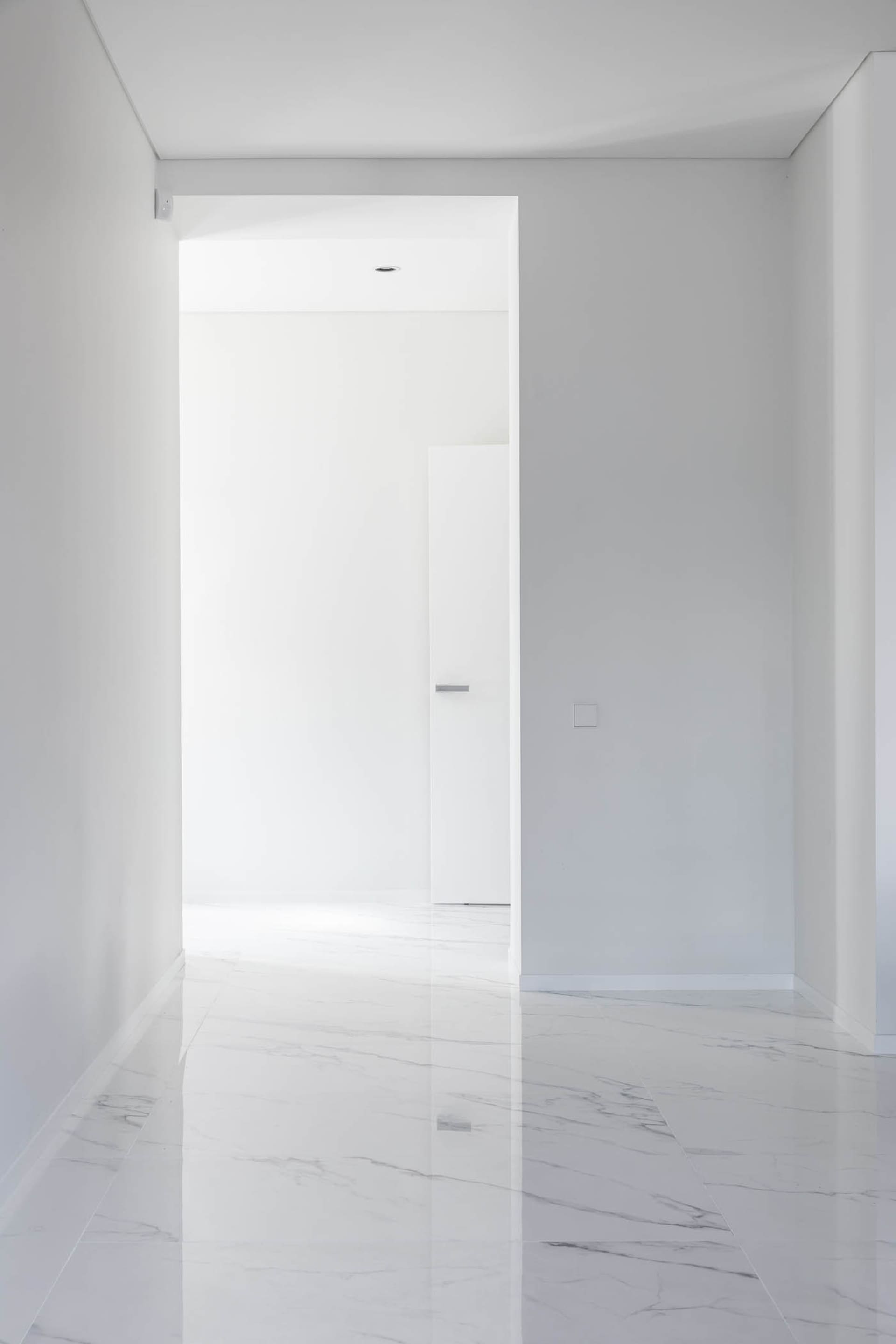 A minimalist, modern interior featuring a marble flooring and white walls.