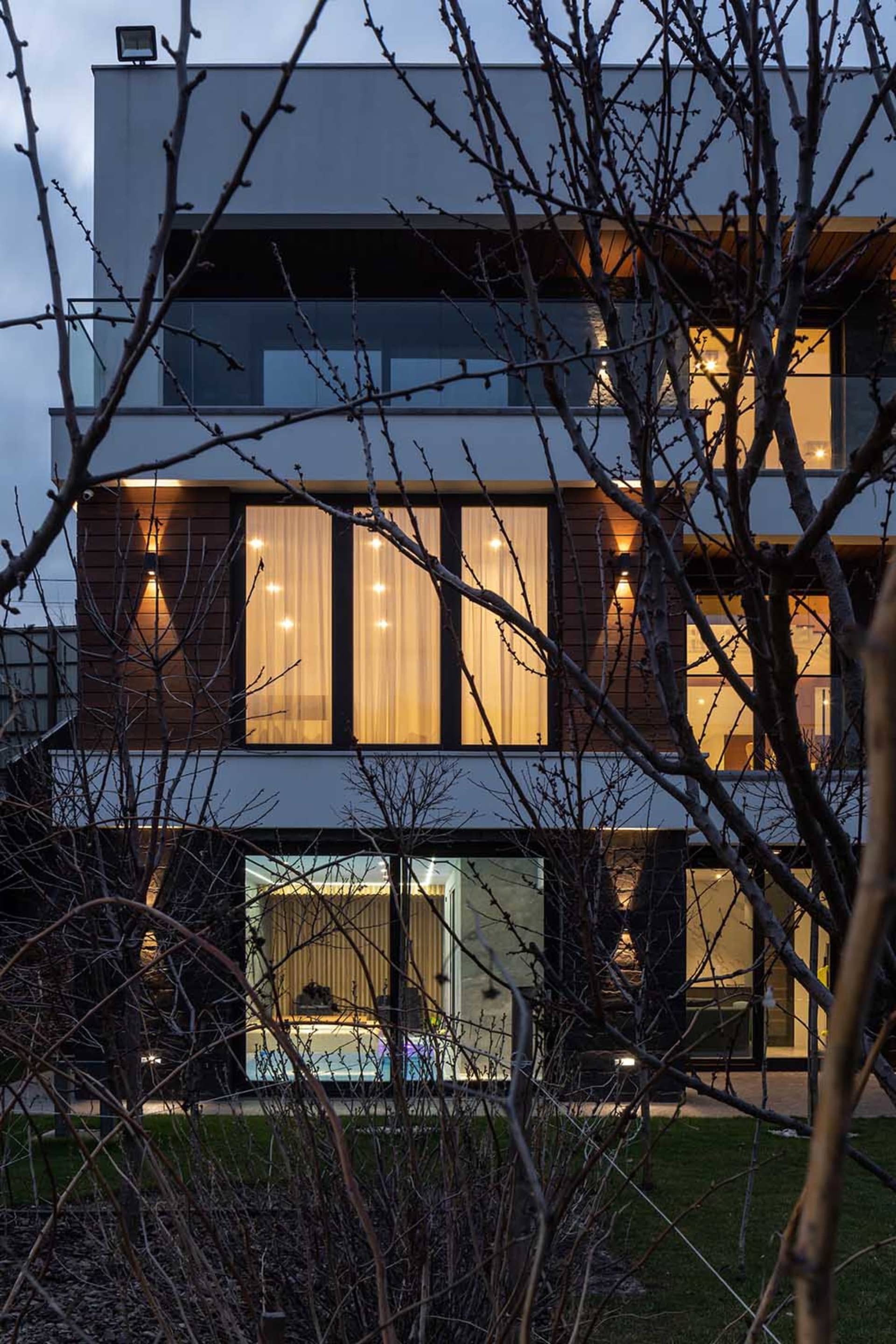 A modern residential building with large glass windows and wooden siding.