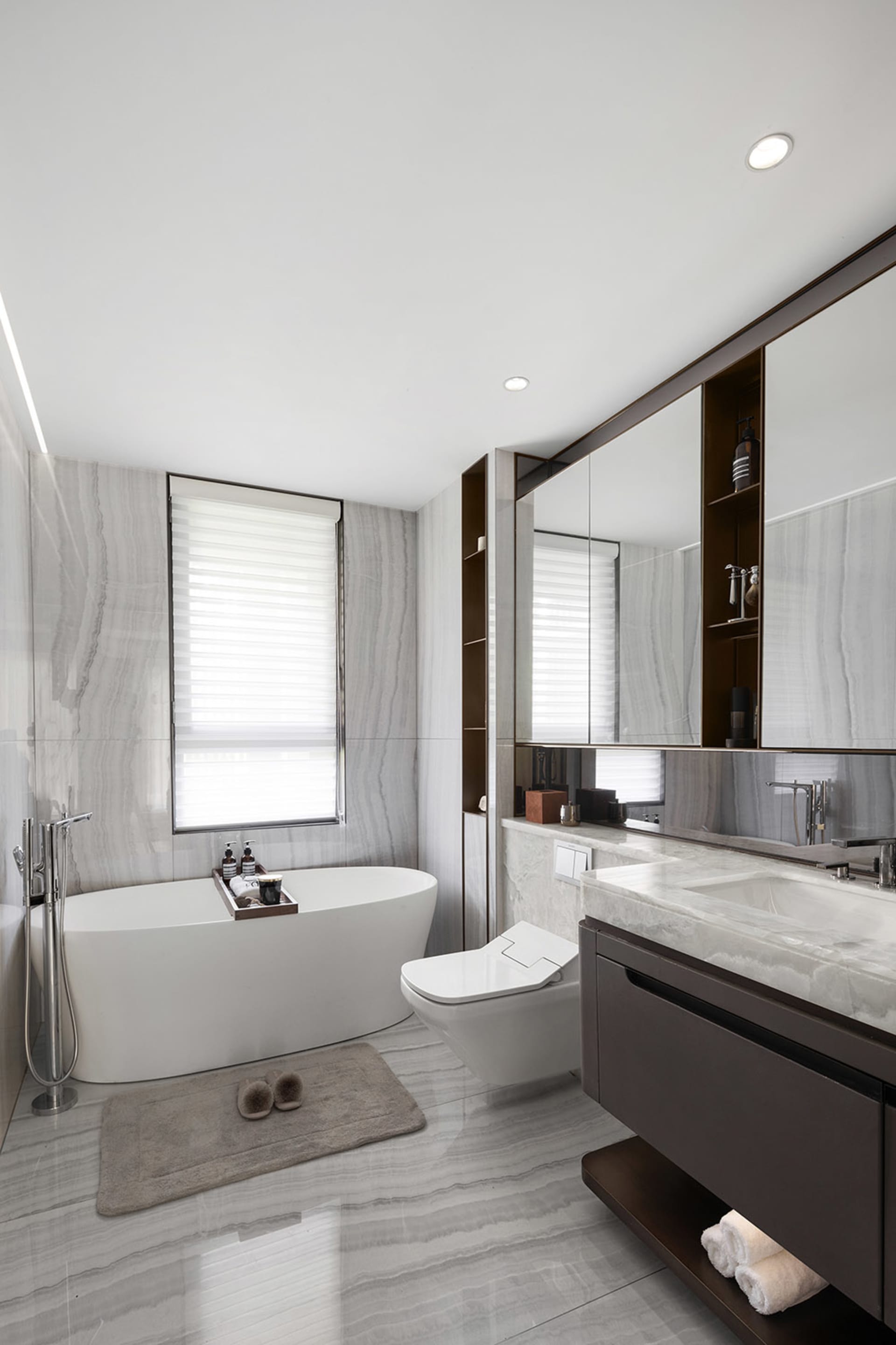 A modern bathroom featuring a freestanding tub, toilet, and vanity with a large mirror.