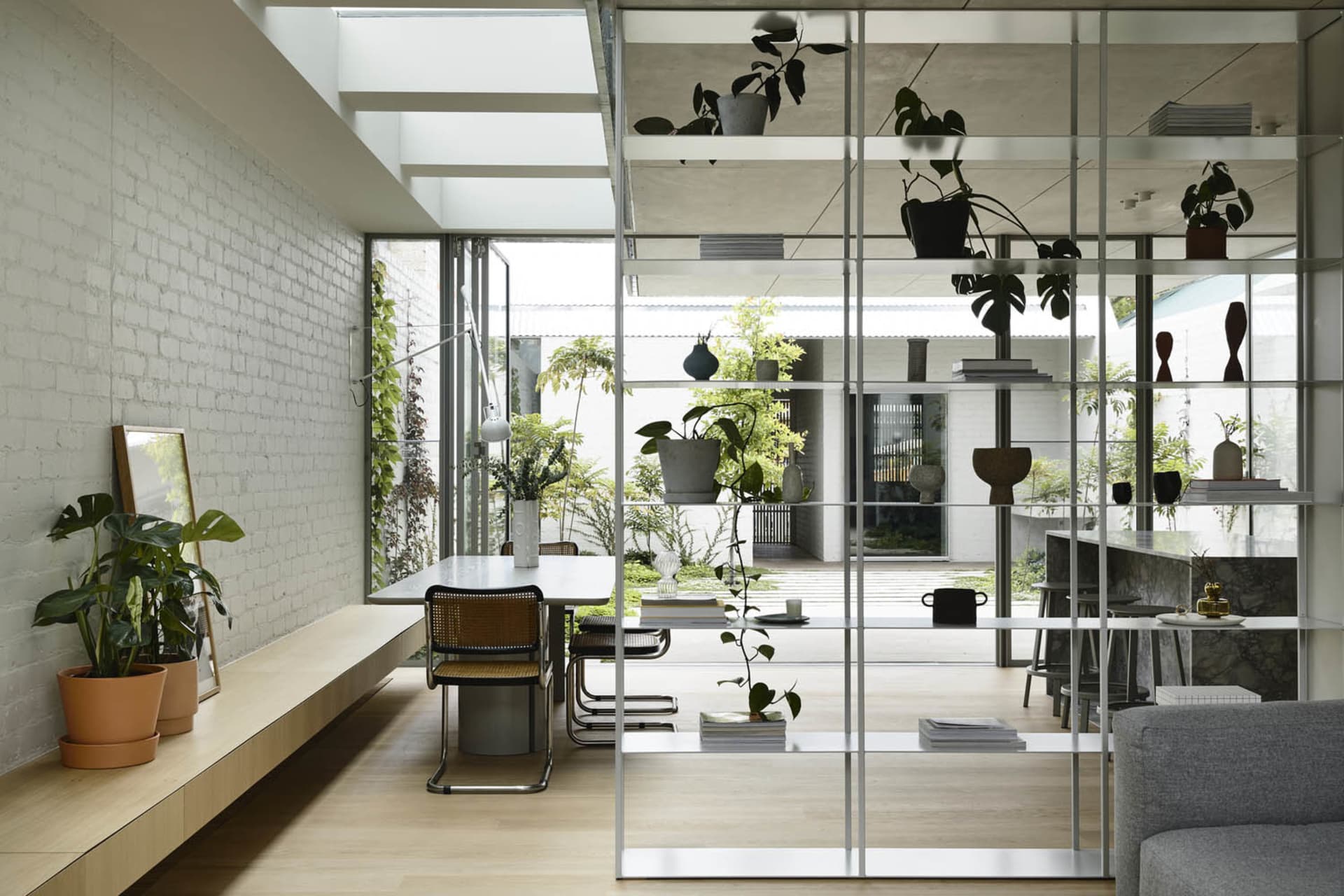 Industrial-style living space featuring exposed concrete walls and shelves filled with plants and decorative objects.