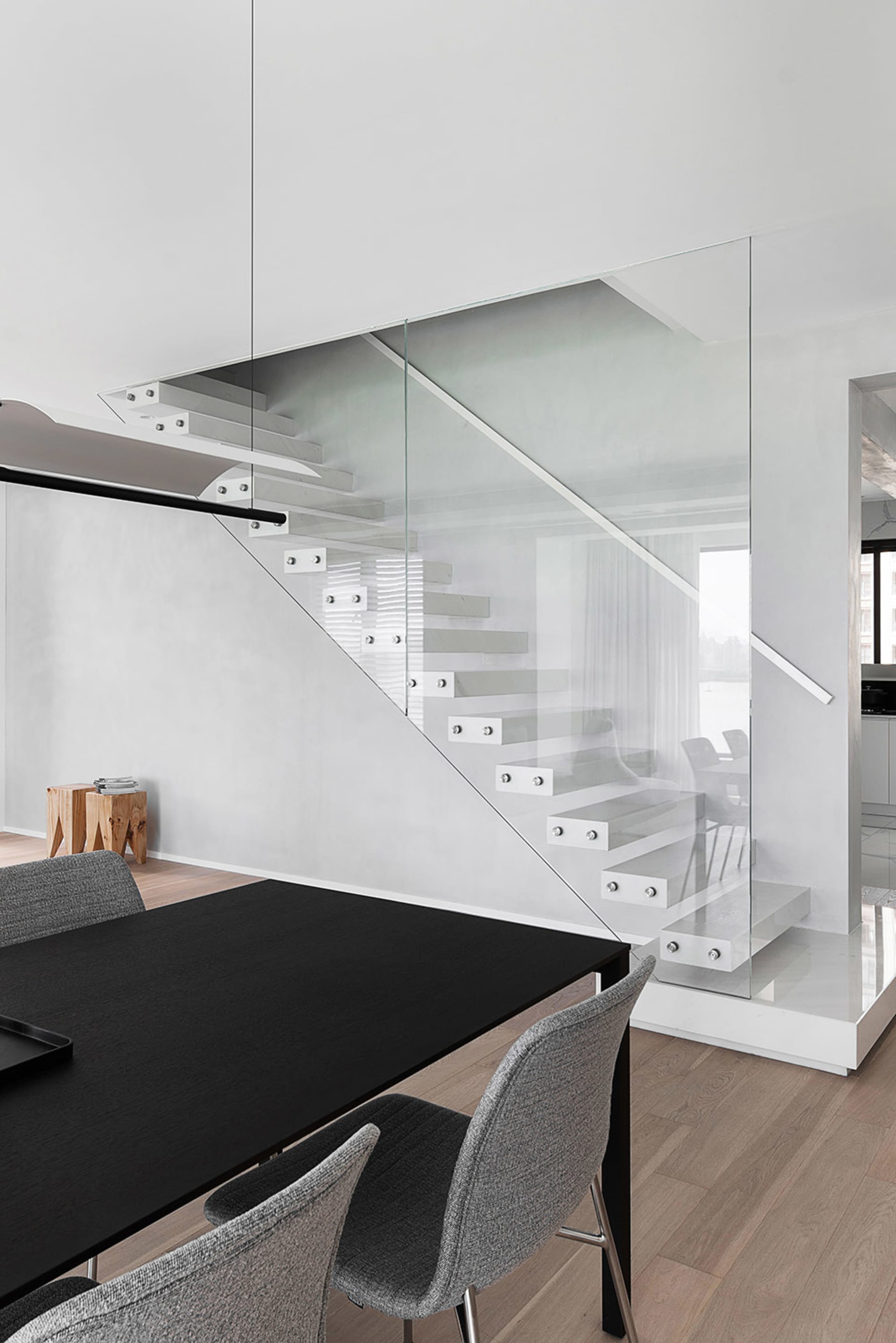 Modern dining room featuring a glass and metal staircase