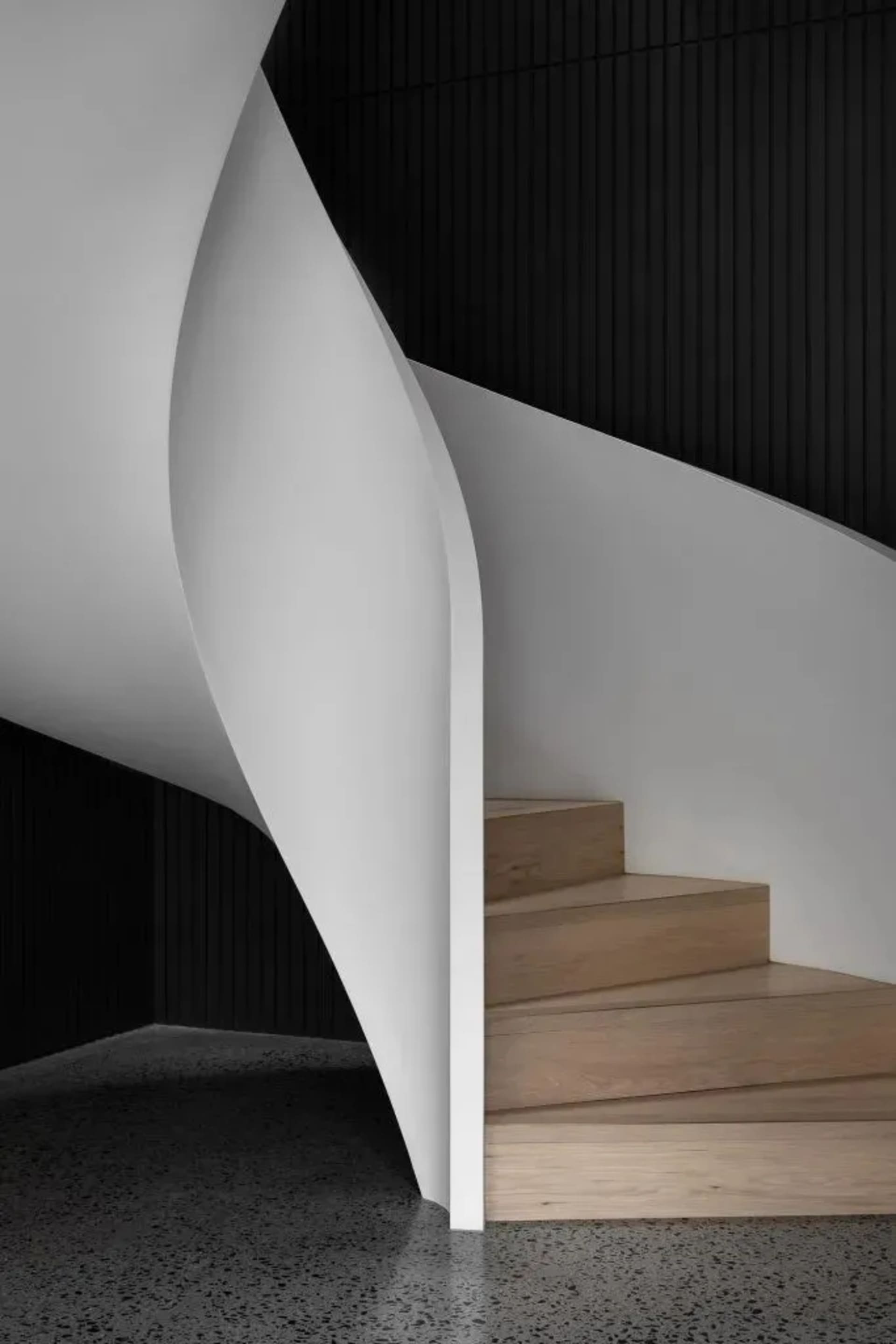 Modern industrial interior with concrete walls and a wooden staircase.
