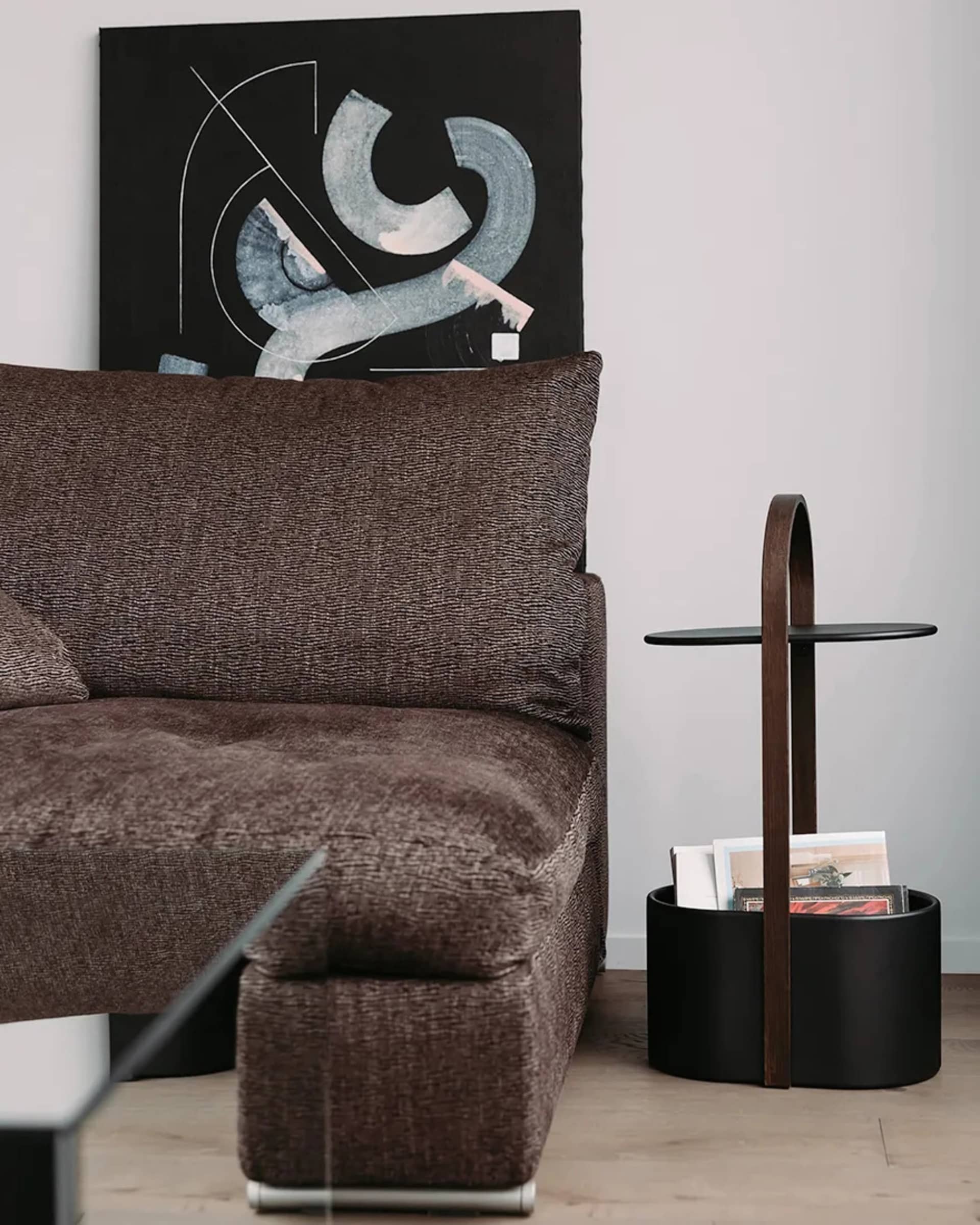 A modern living room featuring a fabric sofa, abstract artwork, and a side table.