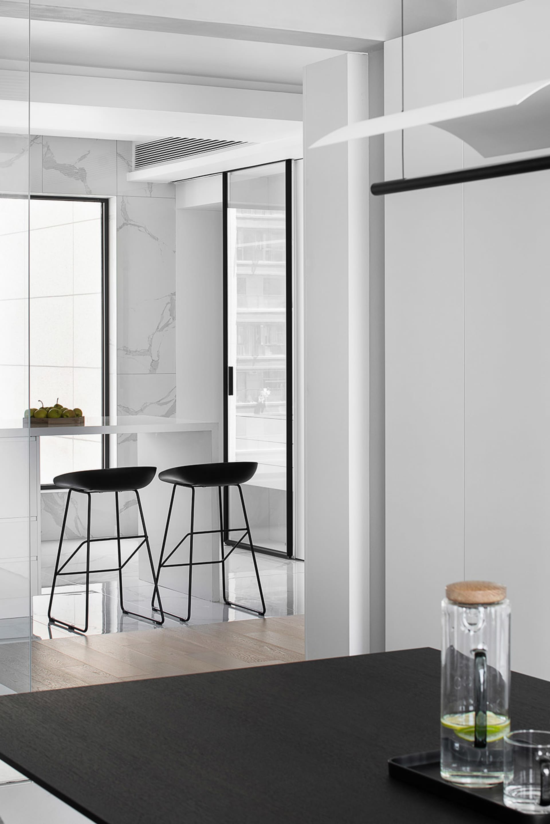 A modern kitchen and dining area with black stools and marble surfaces.