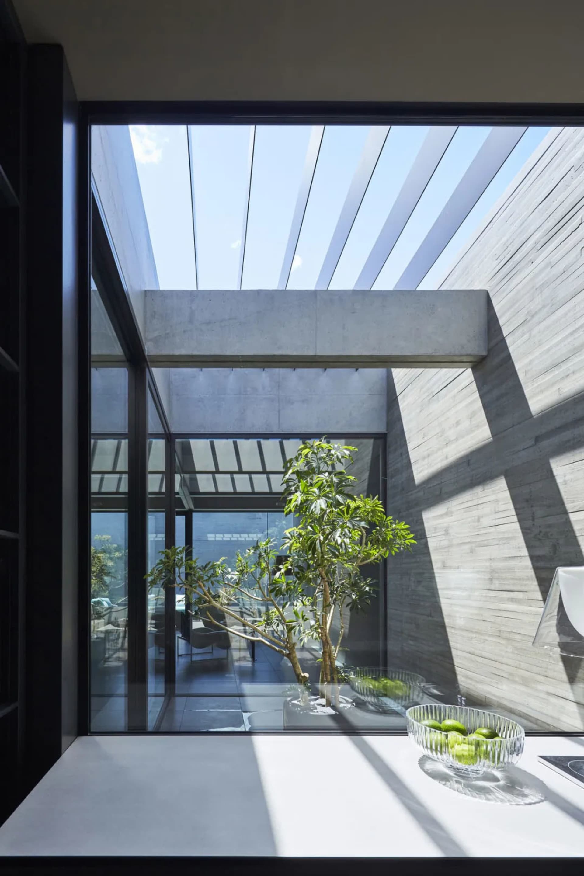 A modern house with a concrete structure, featuring large windows and a skylight.