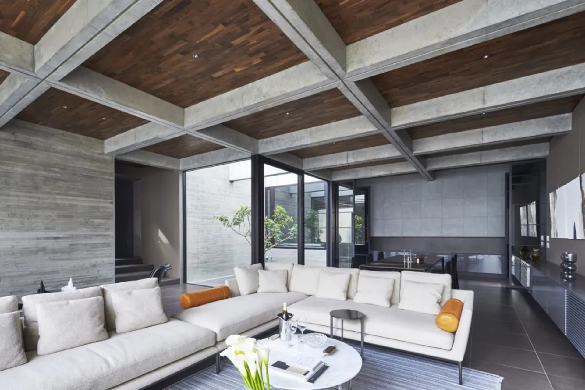 Modern industrial living room with concrete ceiling, white furniture, and open space.