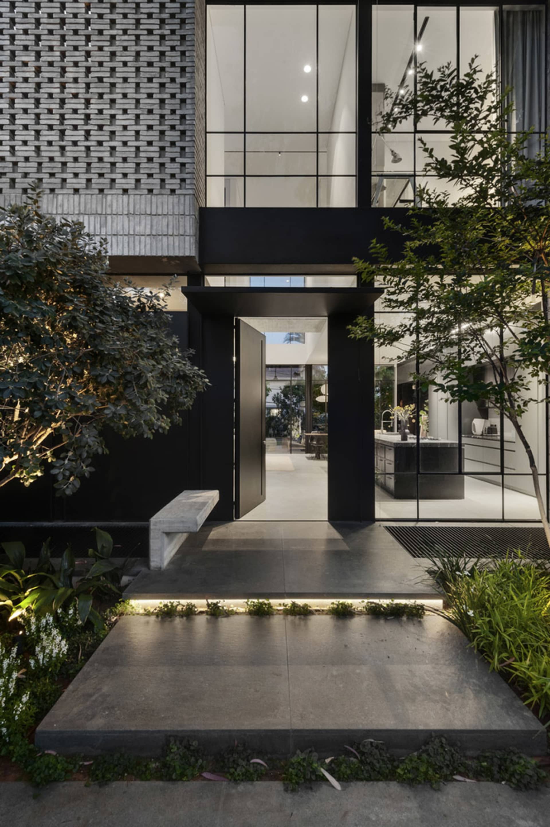 A modern entrance with a concrete floor and black-framed glass doors.