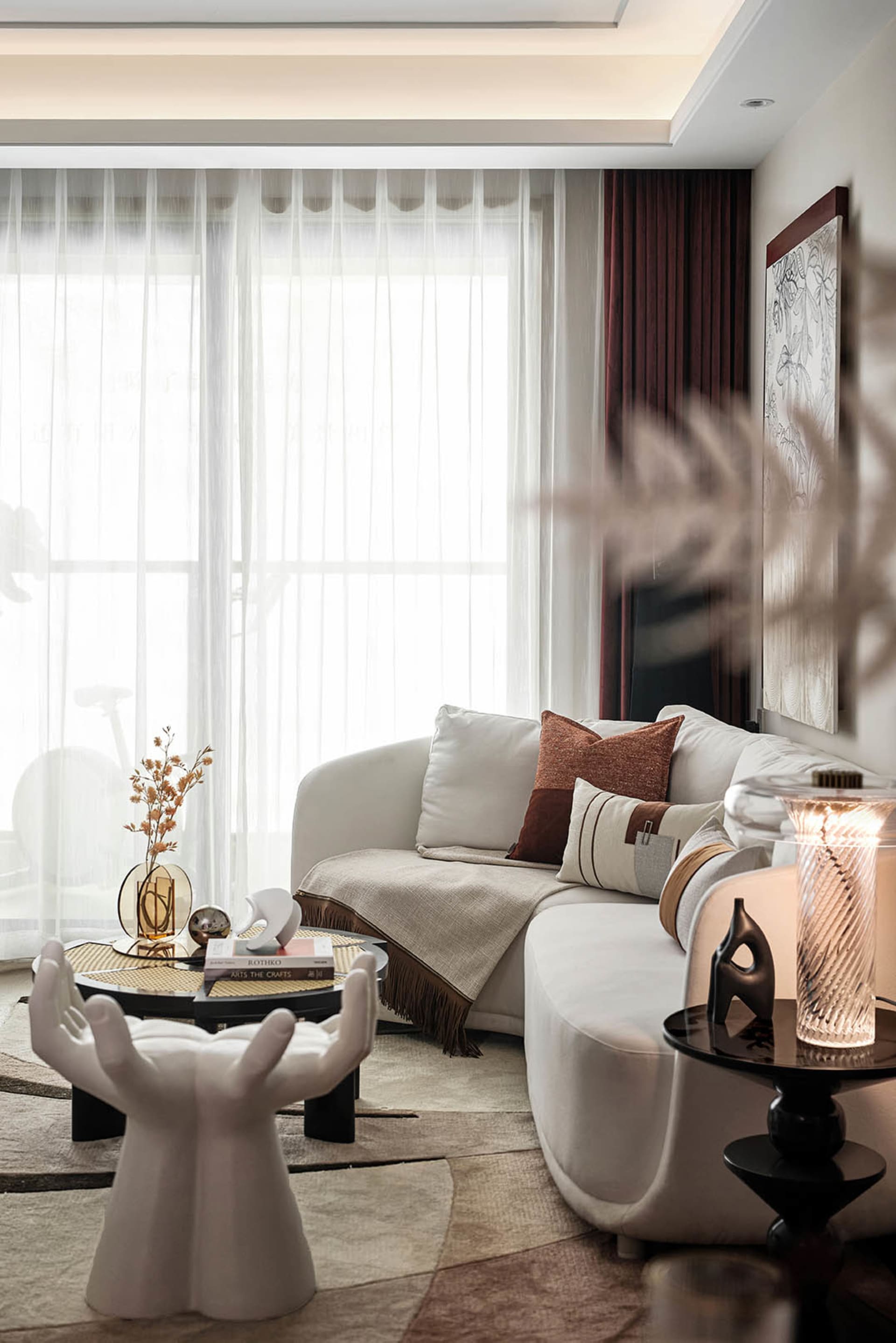 Modern living room with a white couch, geometric coffee tables, and neutral-toned decor.