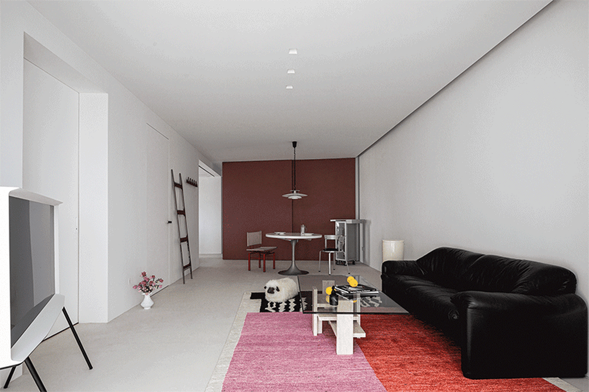 Modern minimalist living room with sleek black sofa, glass coffee table, white walls, and red carpet
