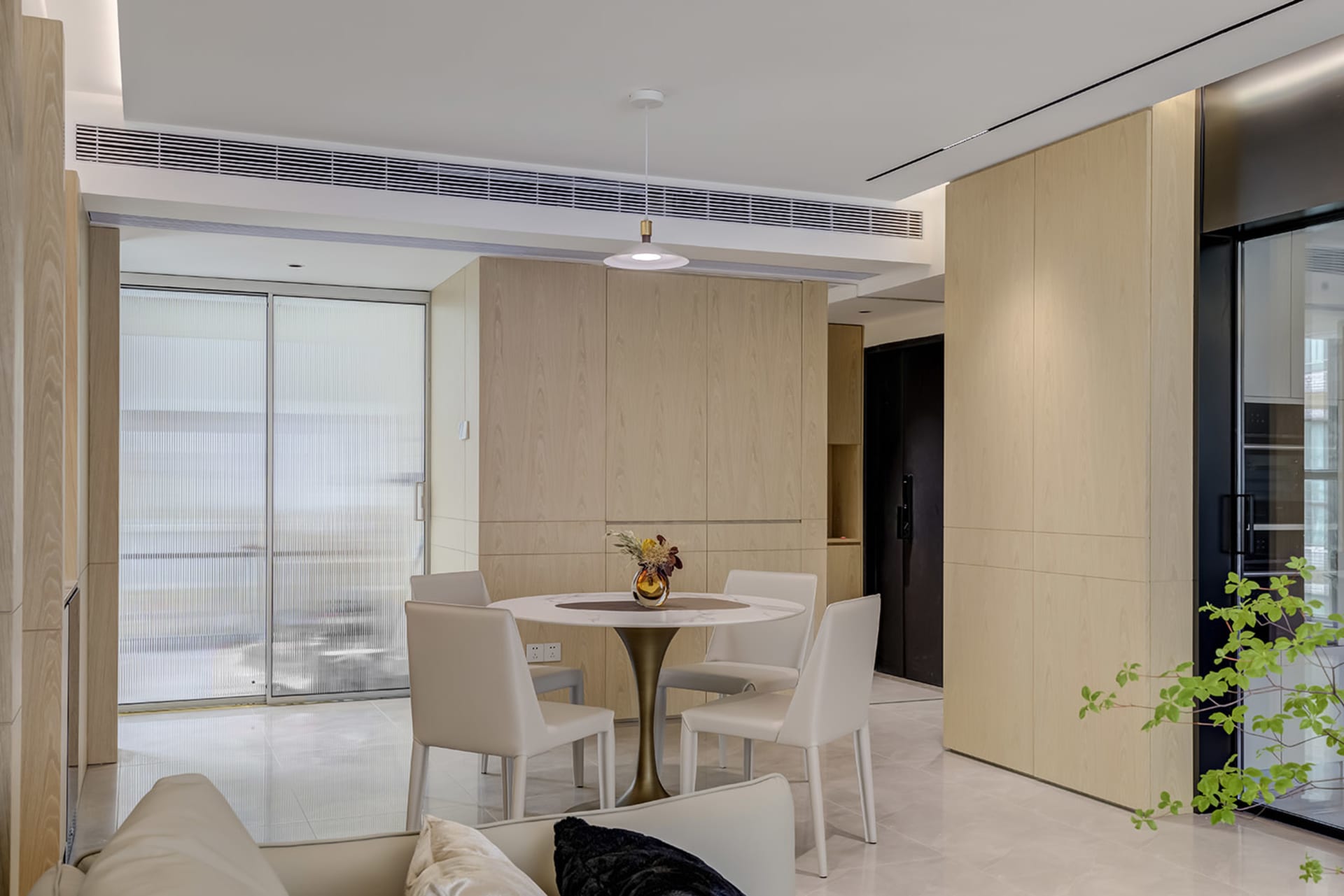 Modern kitchen interior with wooden cabinets, white marble countertop, and white chairs around a round table.