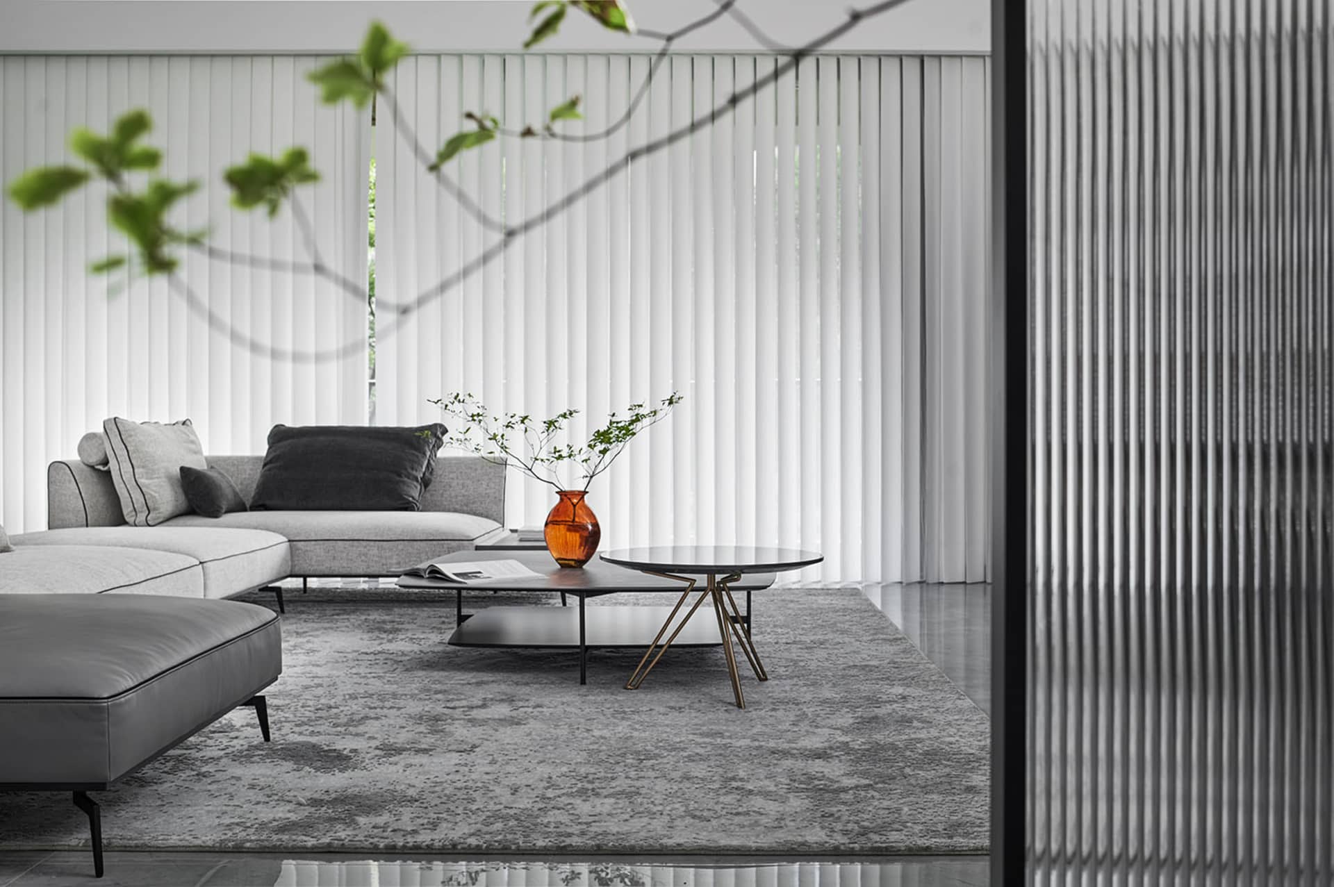 Modern minimalist living room with grey sofa, black coffee table, and white blinds.