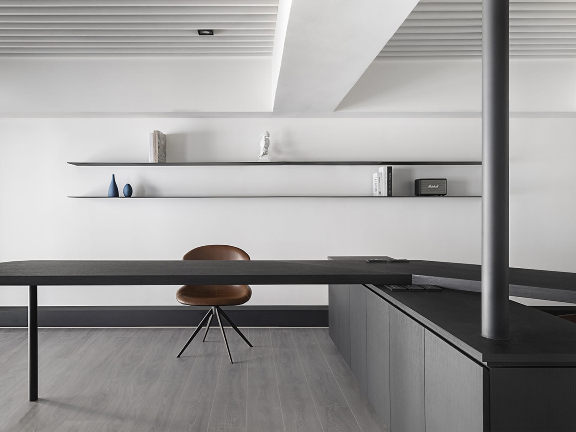 Modern minimalist home office with black wooden desk and floating shelves.