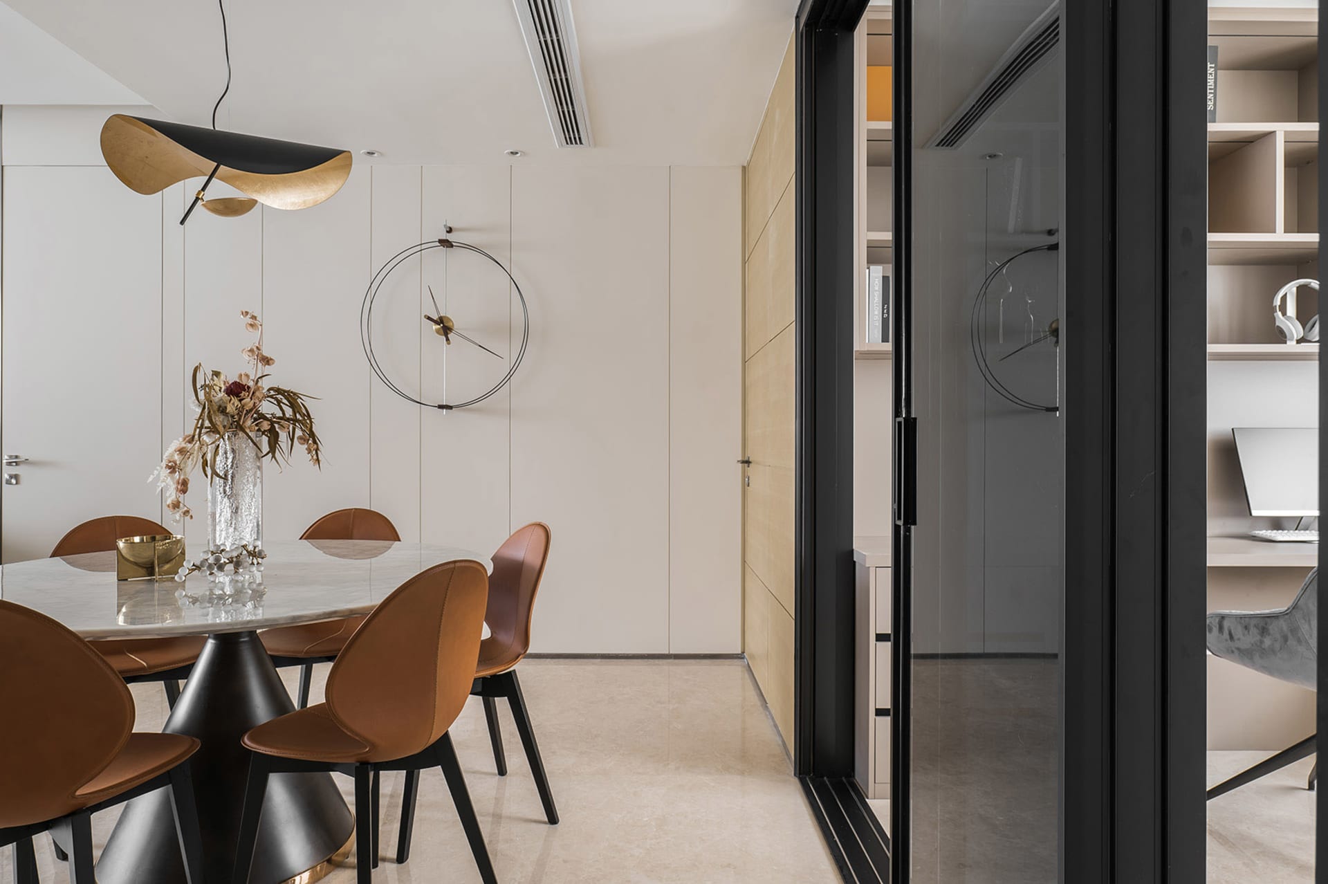 Modern dining room featuring a marble dining table with concrete legs, leather chairs, and a metal pendant light.
