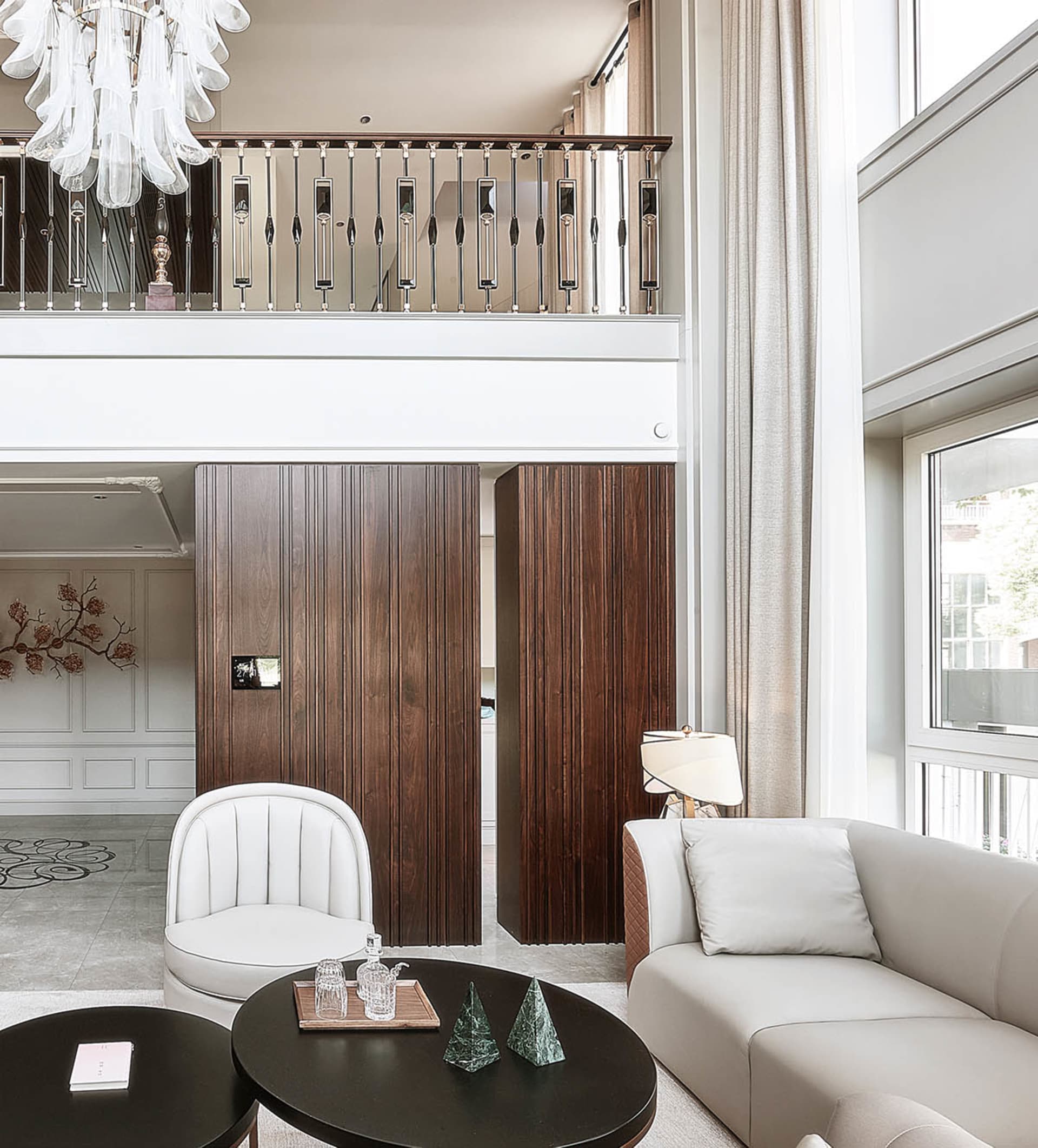 A modern living room featuring white furniture, dark wood panels, and elegant lighting fixtures.