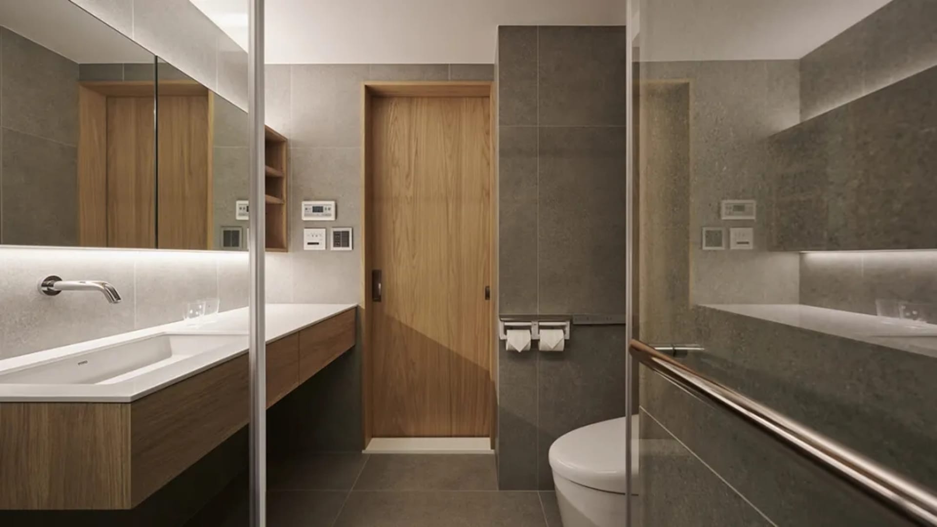 A modern minimalist bathroom with concrete walls and flooring, featuring a sleek sink and toilet design.