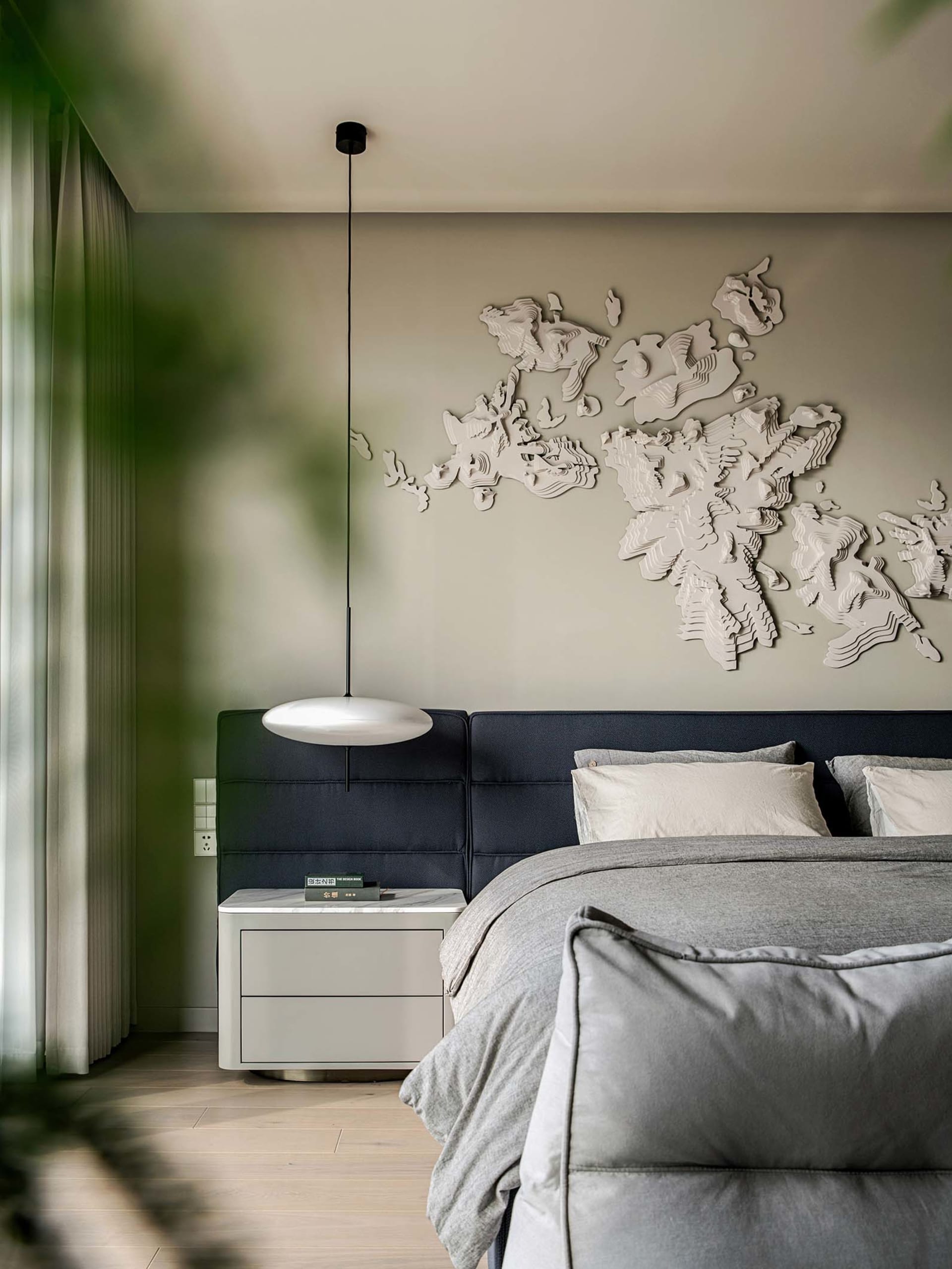 A modern minimalist bedroom featuring a fabric headboard and a wall-mounted decorative world map.