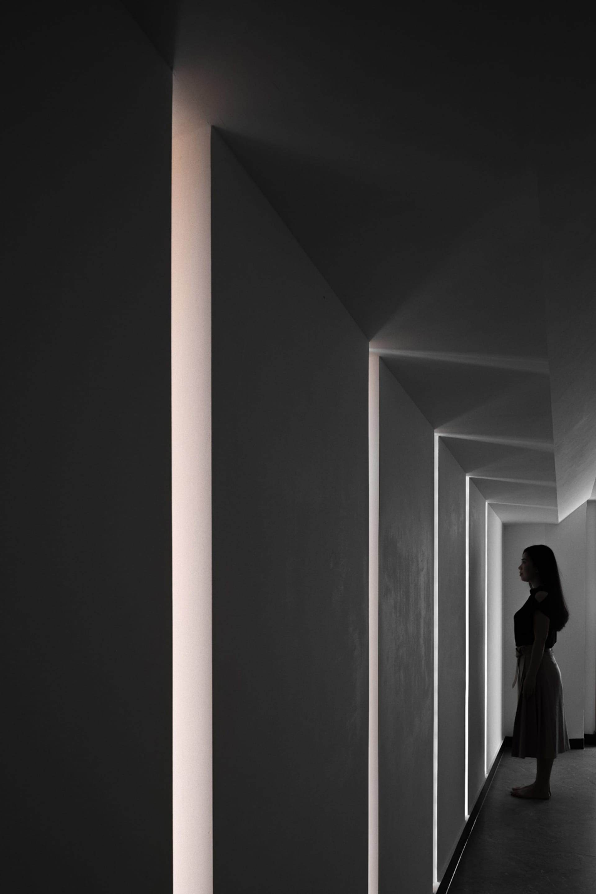 A minimalist interior space featuring concrete walls and illuminated light strips.