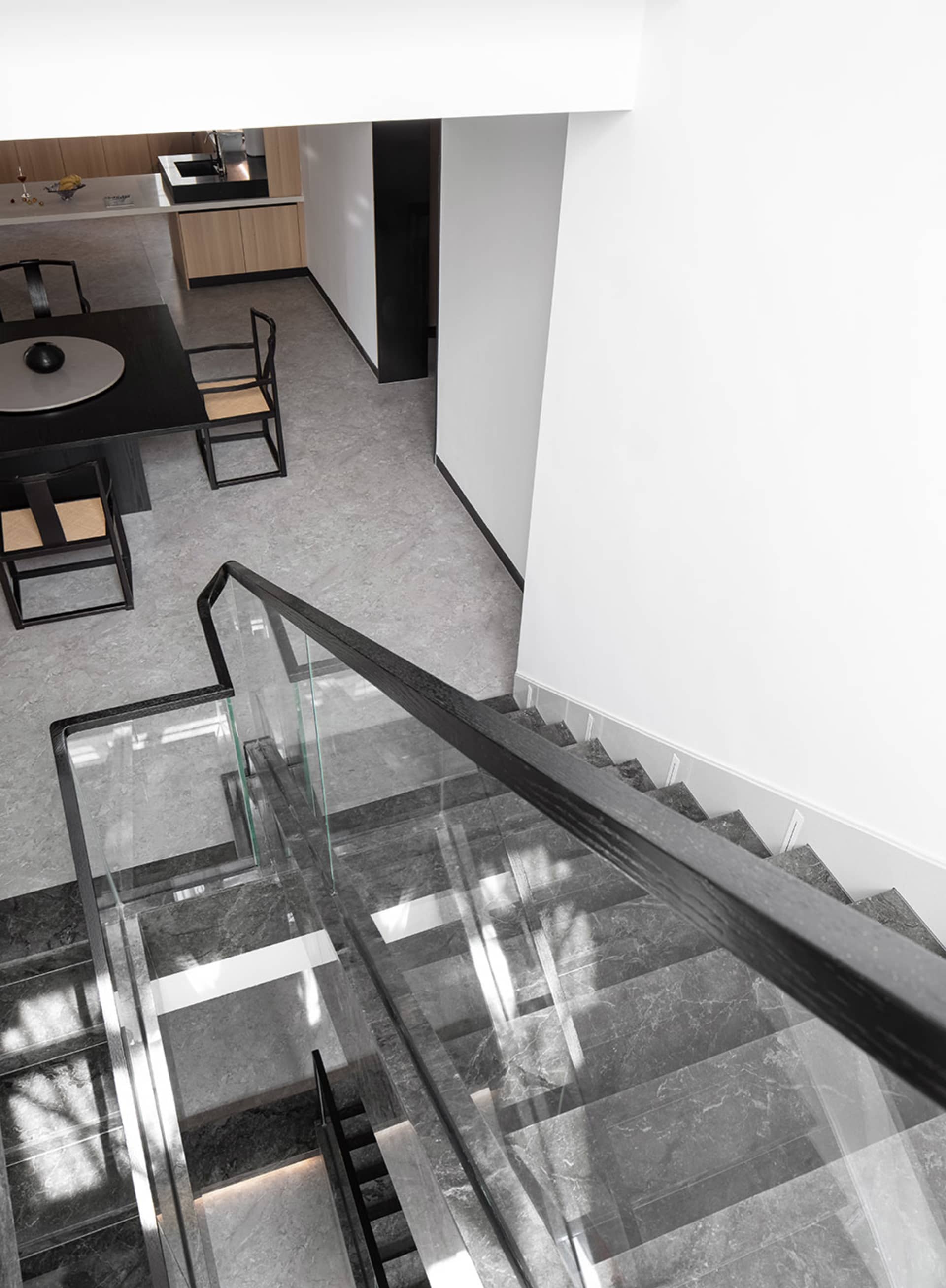 Staircase with glass railing and marble steps in a modern interior design space.