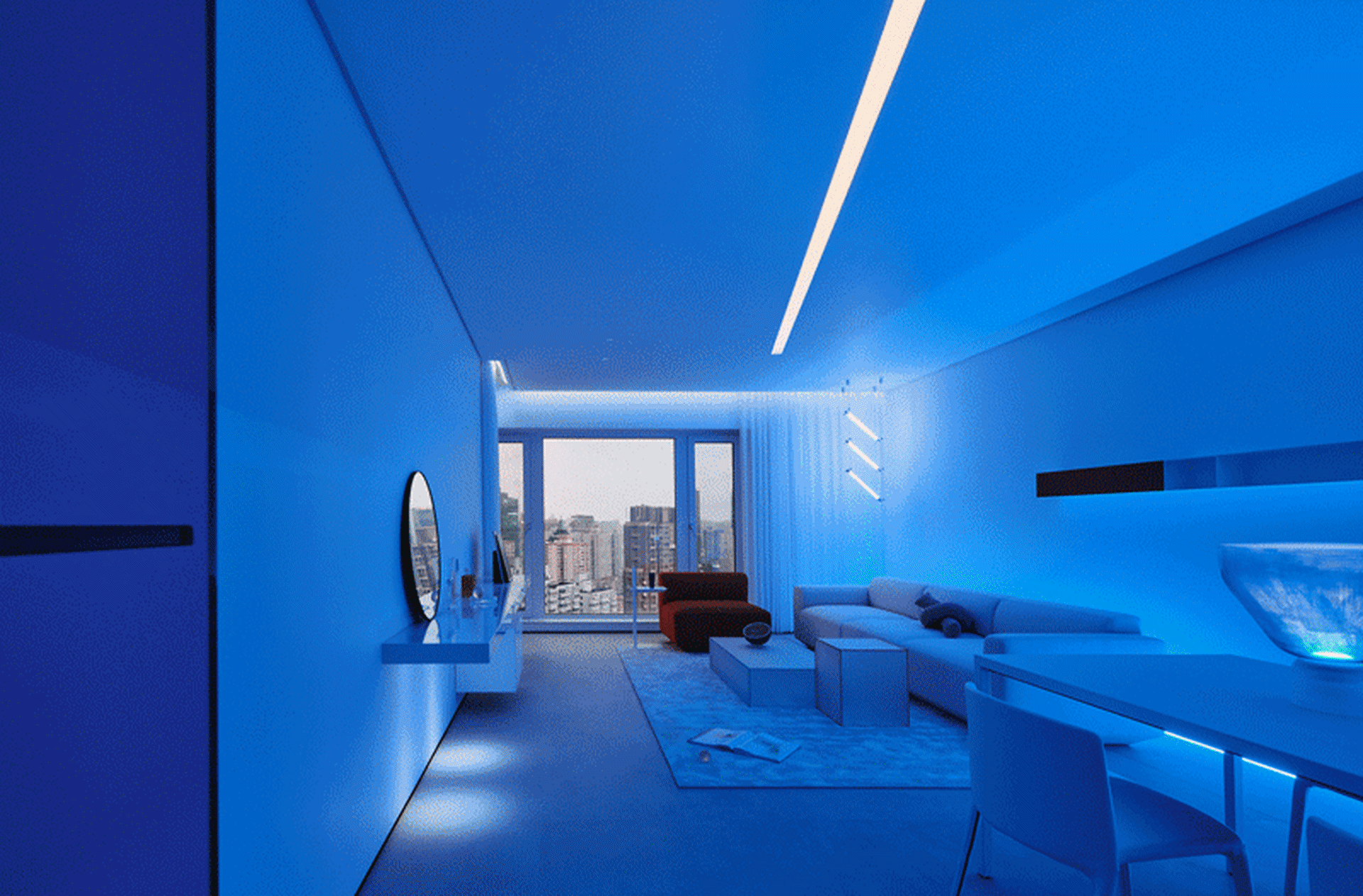 Modern minimalist living room illuminated with blue lights, featuring a sleek, white sofa and minimalistic decor.