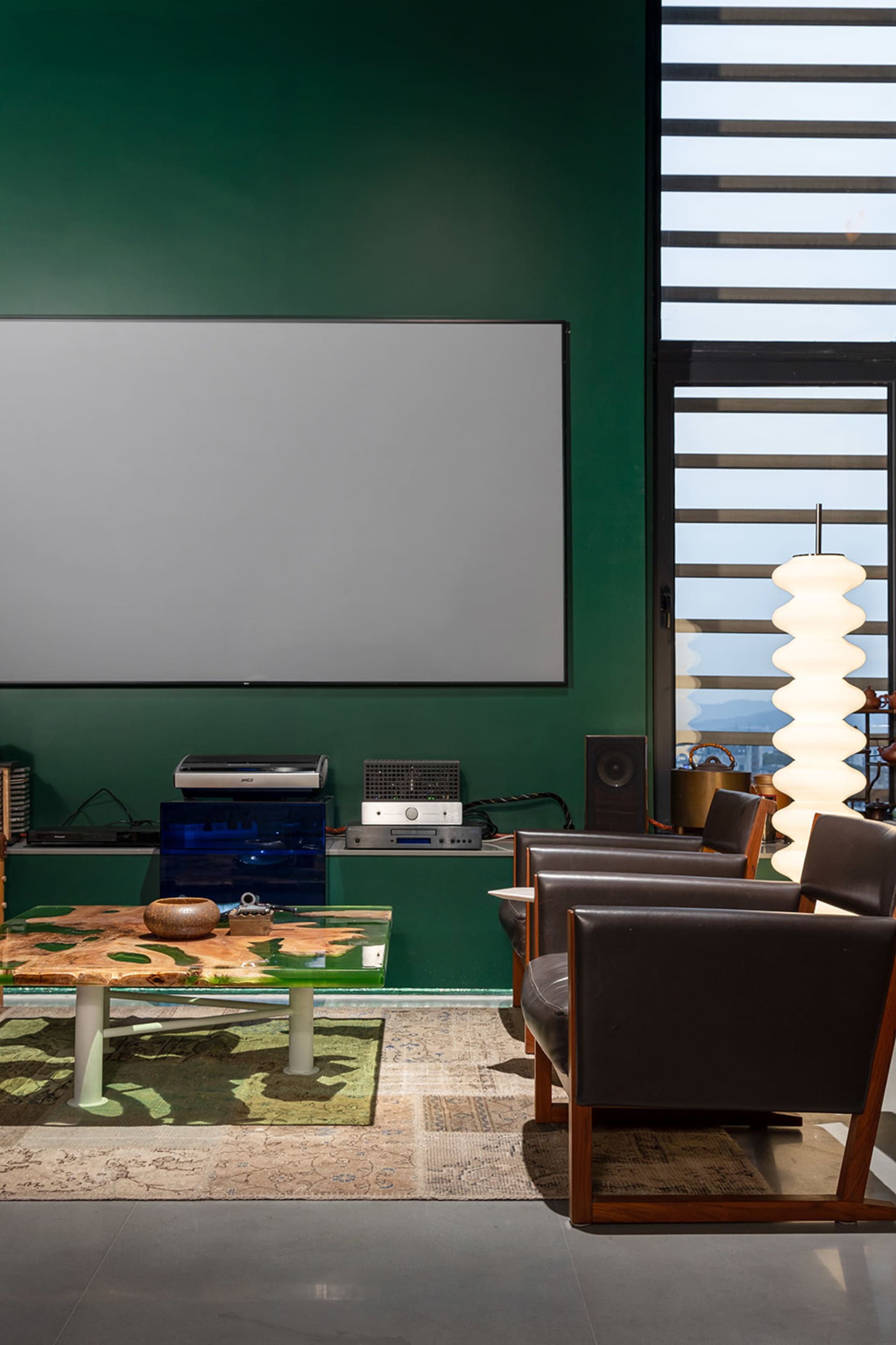 A modern living room featuring metal furniture and a large screen.