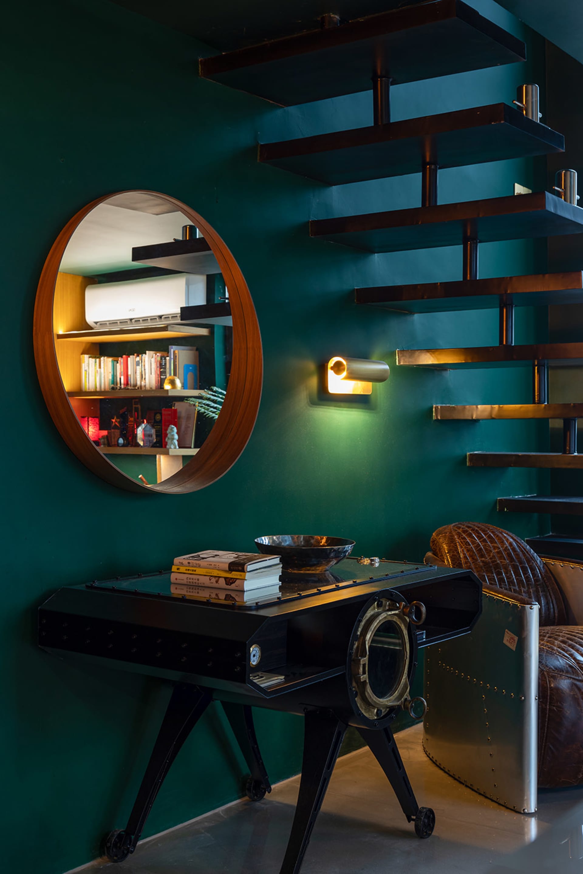 Modern industrial living room with wooden furniture, floating shelves, and circular mirror.
