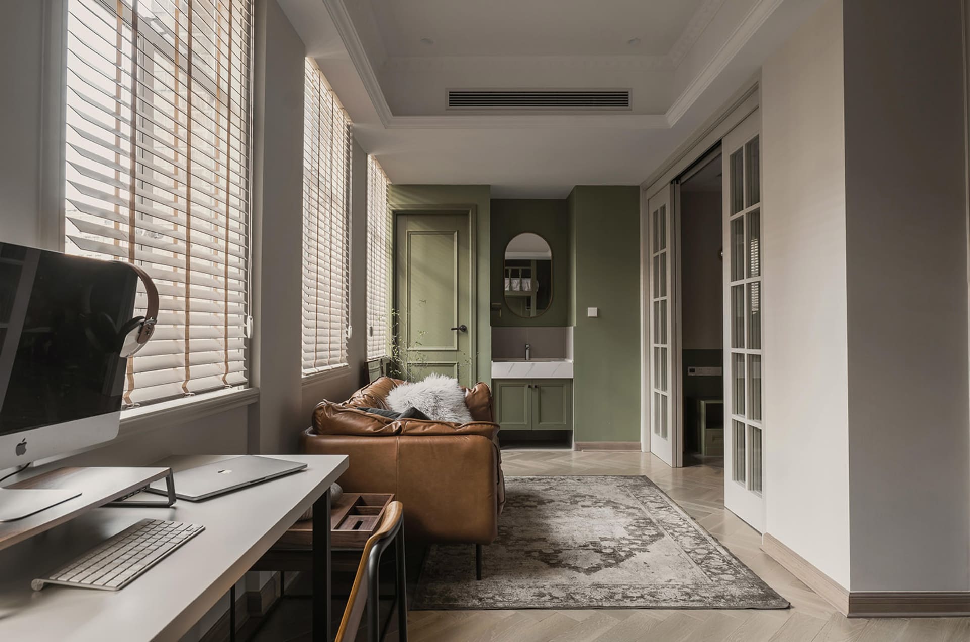 A modern living room featuring a wooden desk, a leather sofa, and textured decorations.
