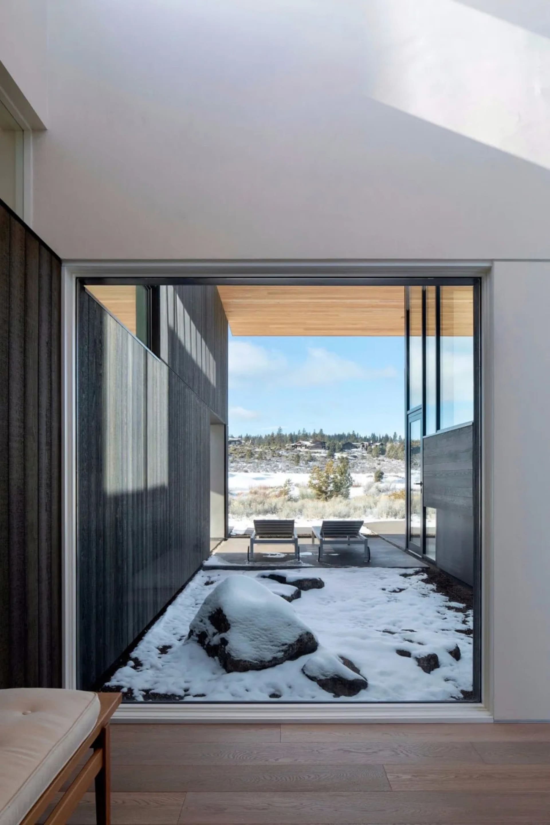 Modern residential interior with glass walls, wood accents, and stone elements.