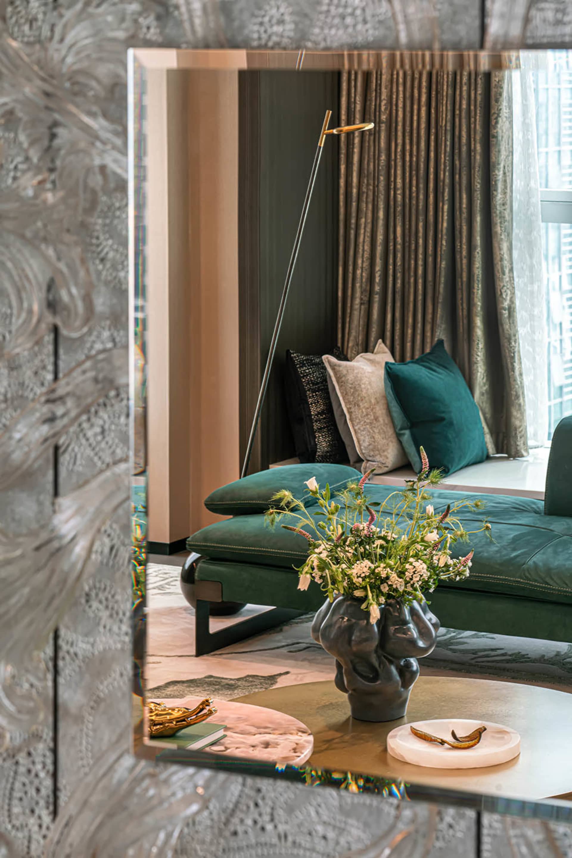 Modern living room featuring a green velvet couch, marble coffee table, and decorative mirror.