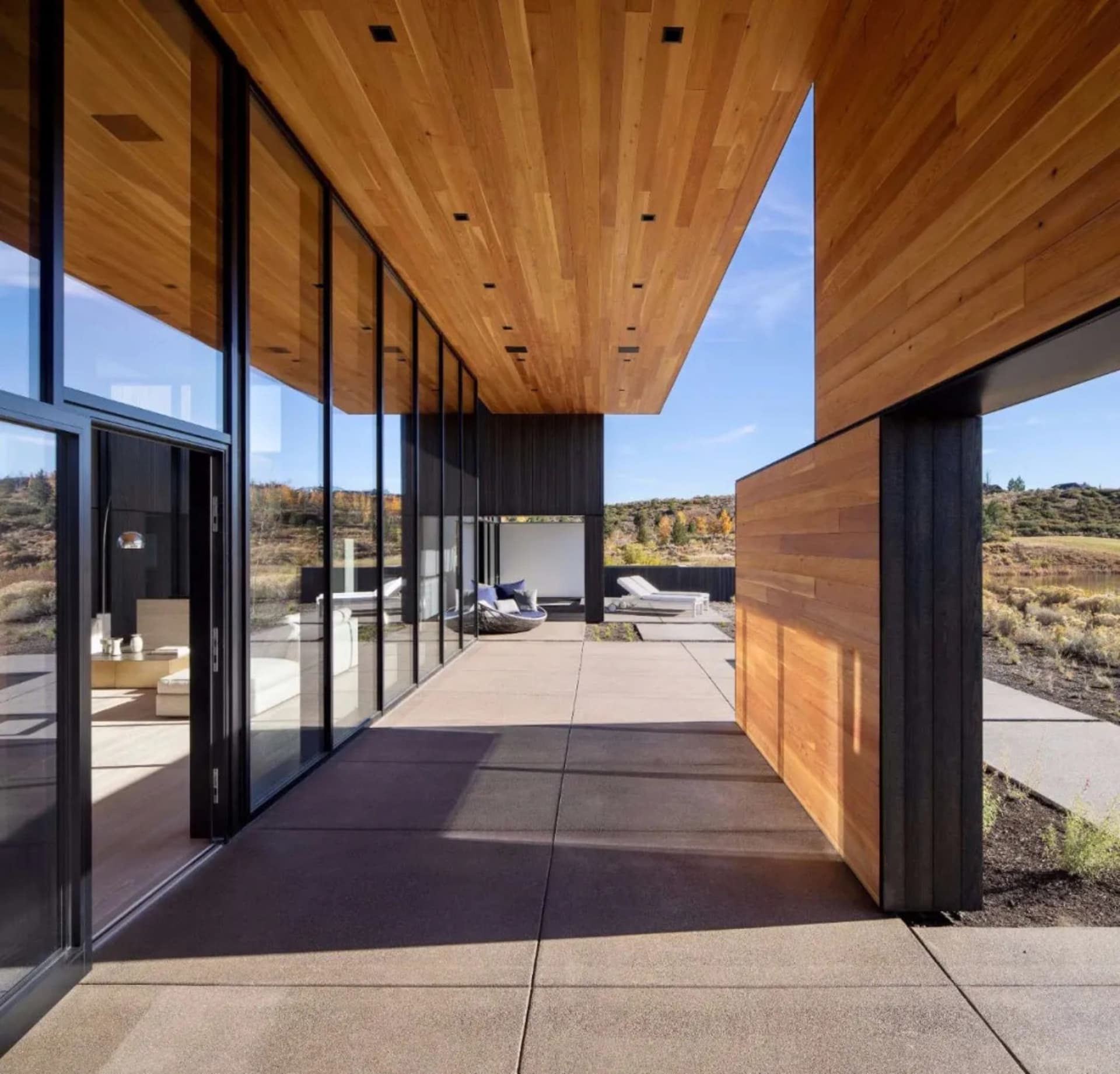 A modern residential patio featuring glass walls, wooden walls, and concrete floor.