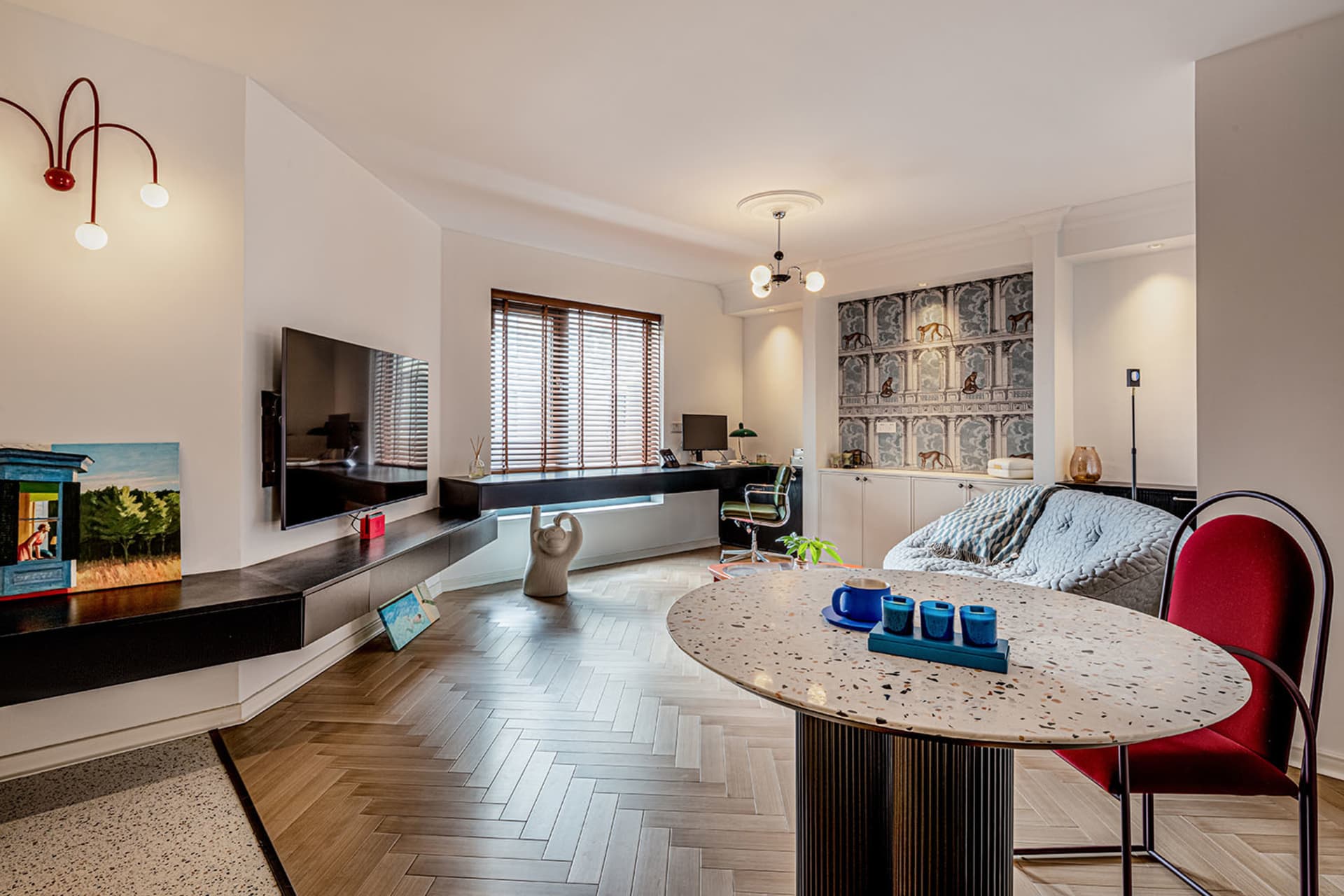 Modern living room with a terrazzo floor, a red accent chair, and a television mounted on the wall.