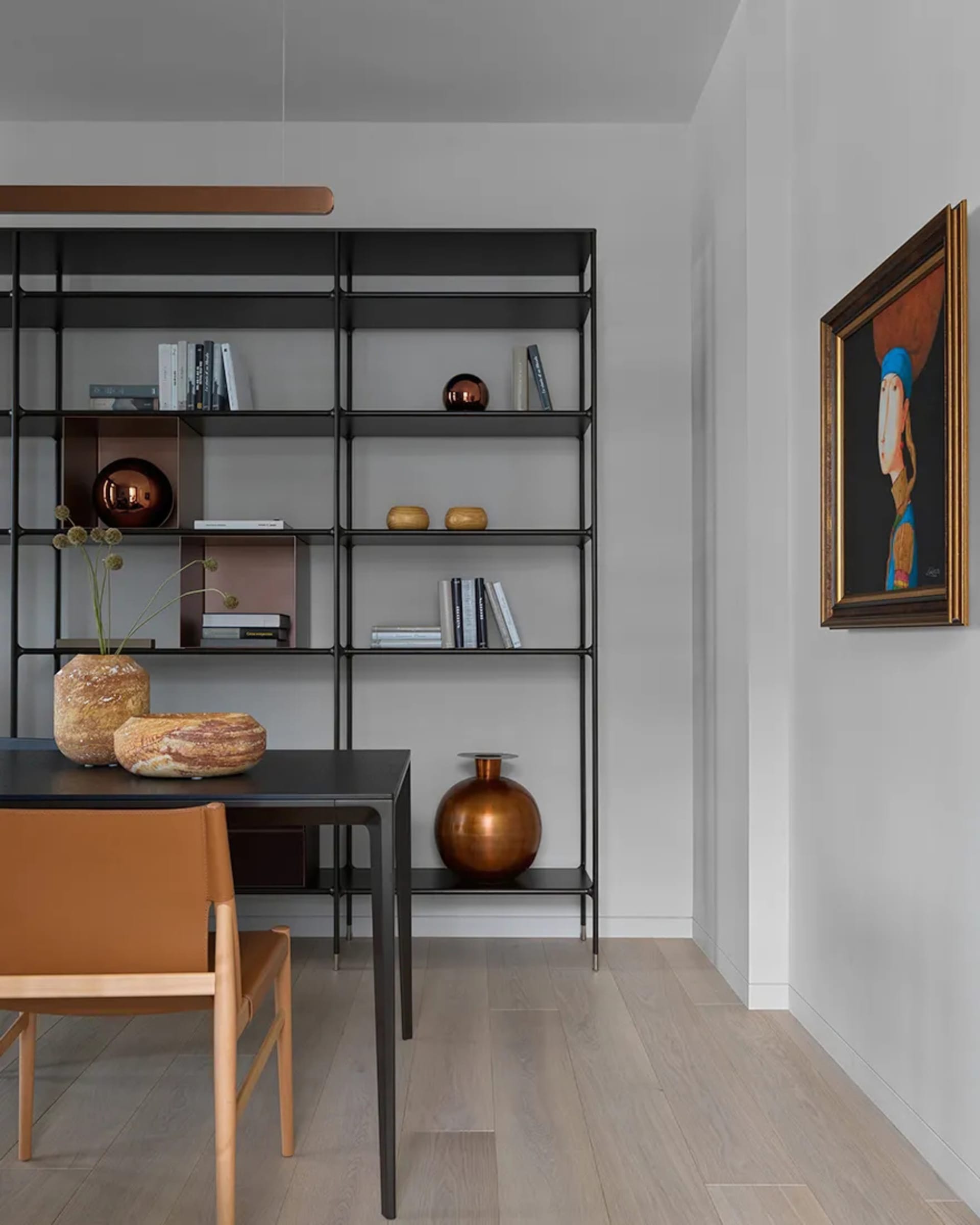 A modern dining room featuring a black shelf unit with metal frames, wood flooring, and ceramic vases.