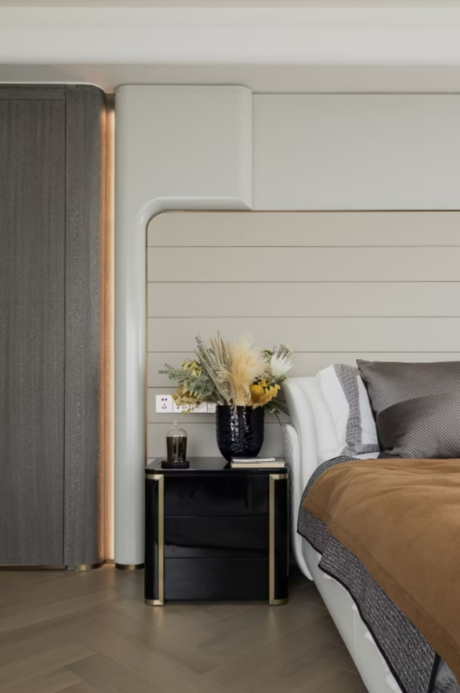 Modern bedroom interior featuring furniture made of wood and metal, adorned with dried flowers in a black vase, and a comfort
