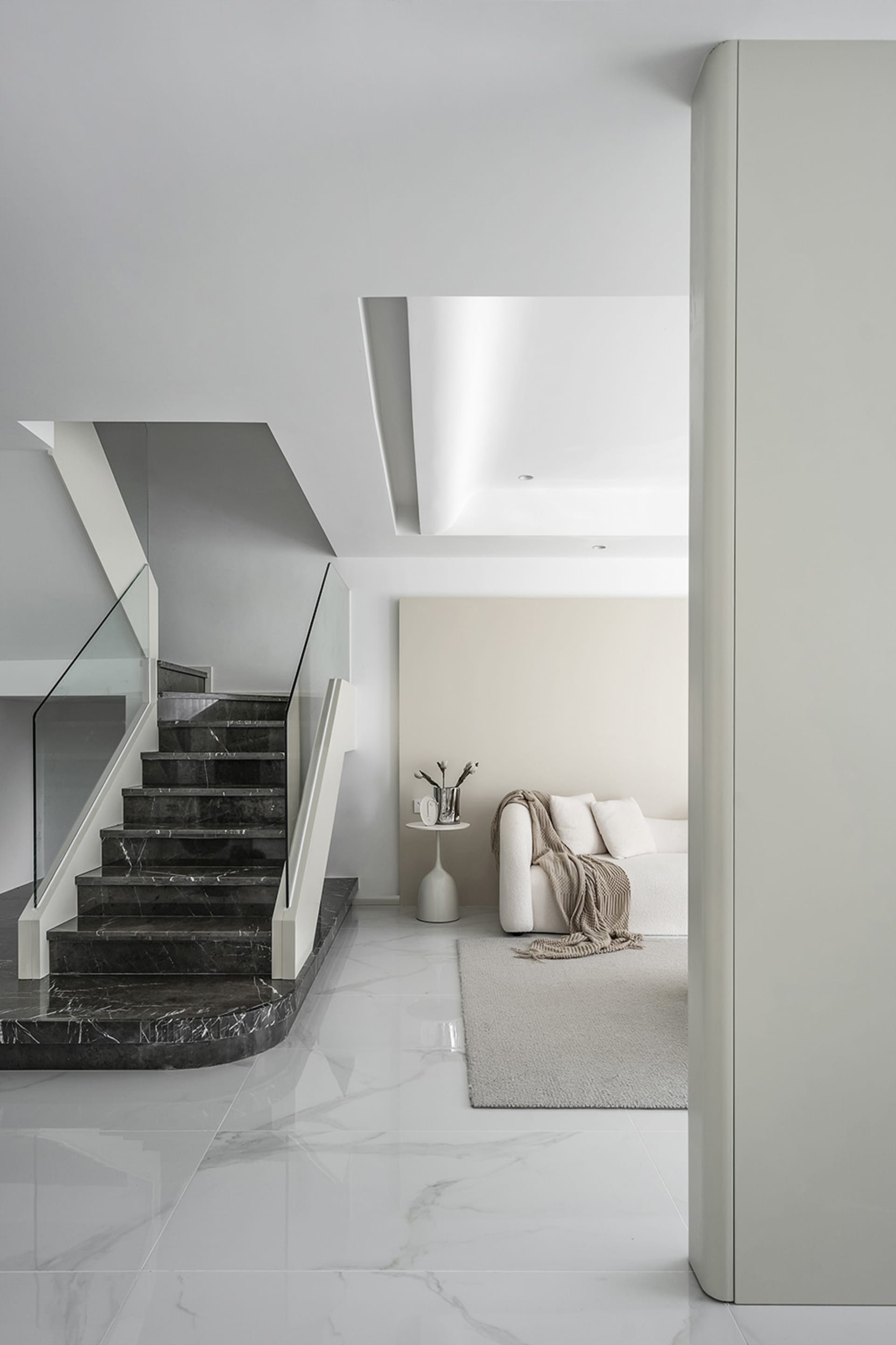 Modern minimalist living room with black marble stairs and white marble flooring.